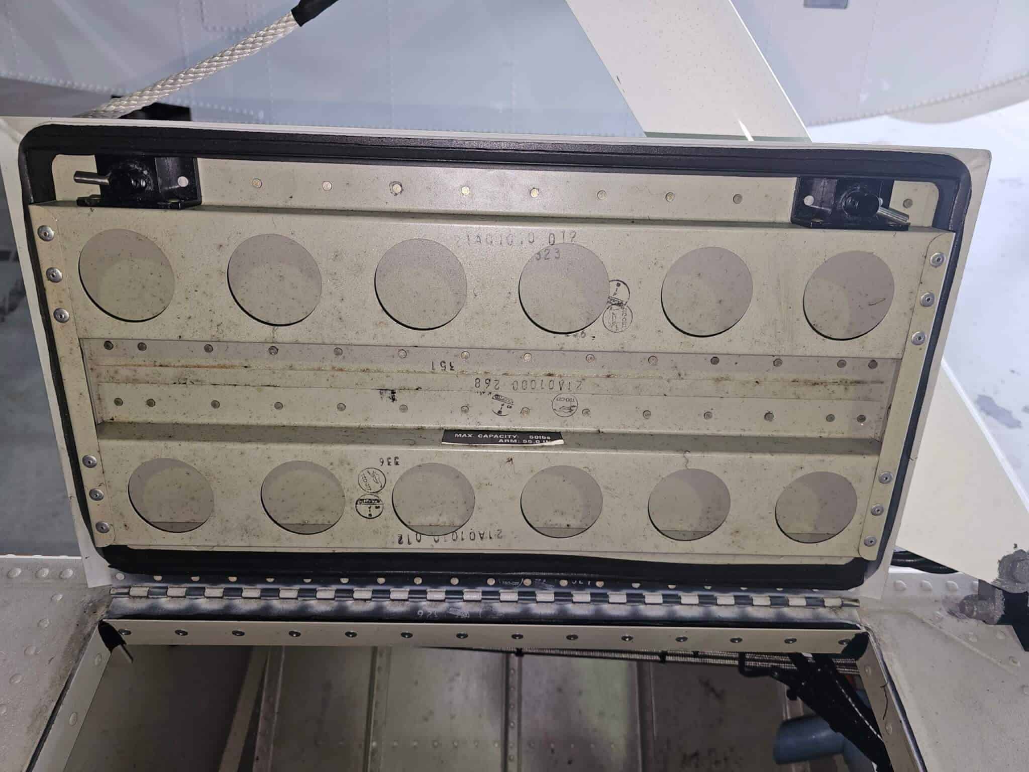 Close-up of an aircraft access panel used for pilot gear storage and maintenance.