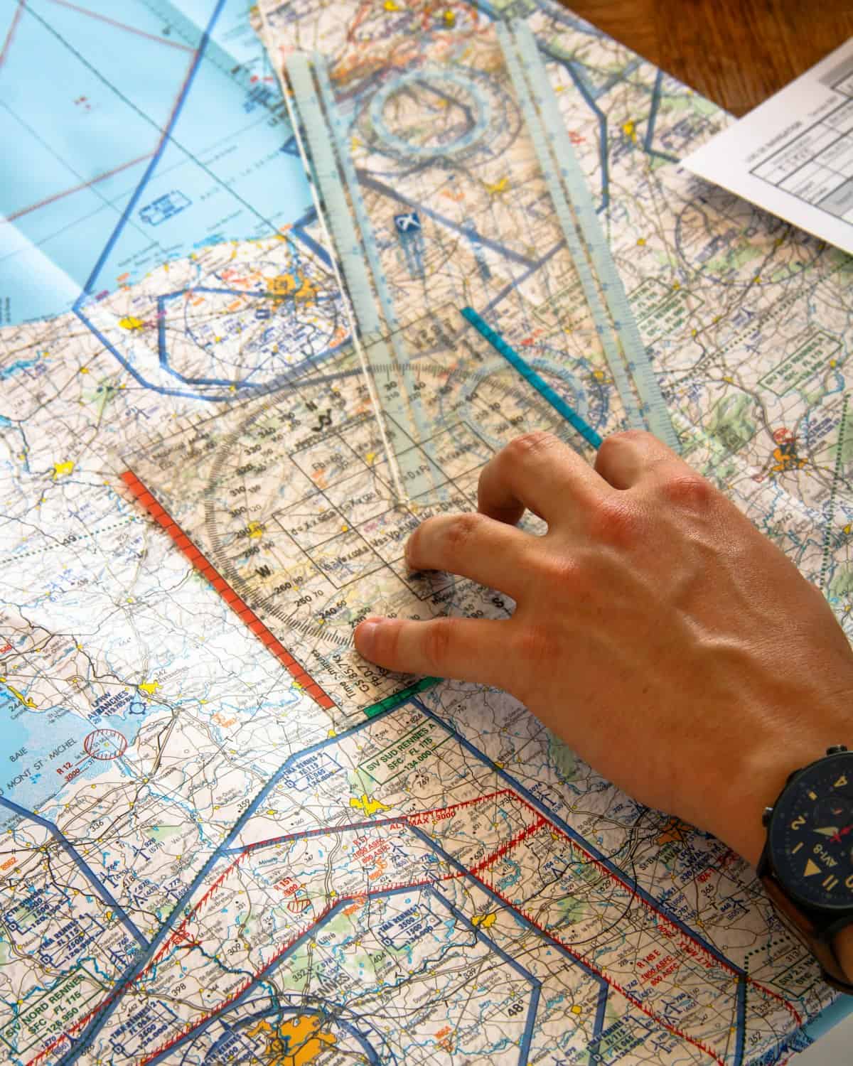 Pilot using ruler on aviation sectional chart to plan route through class b airspace
