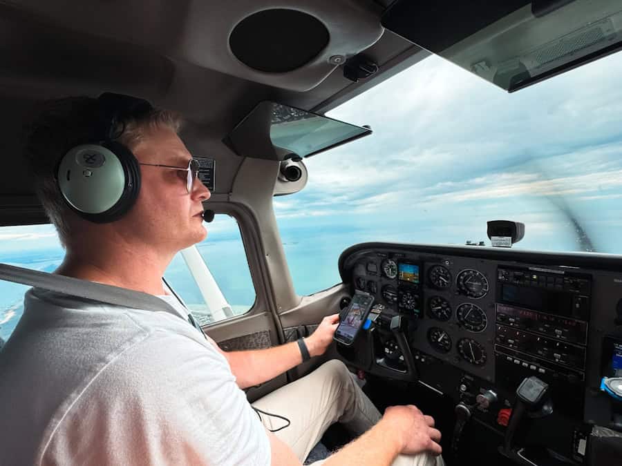 Pilot in cockpit wearing headphones, focused on flying the aircraft.