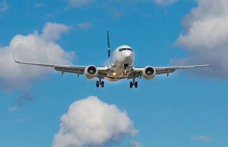Aircraft approaching for landing against a blue sky with clouds.