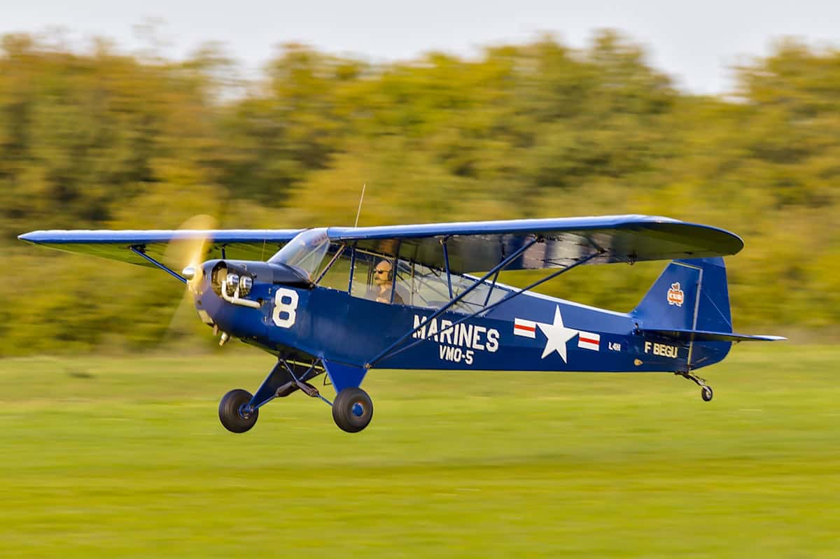 Aircraft flying low with open landscape background.