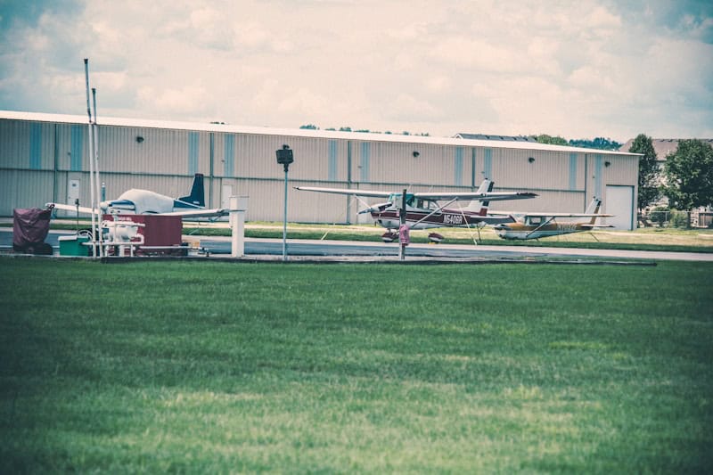 Small aircraft parked near a hangar at an airport.