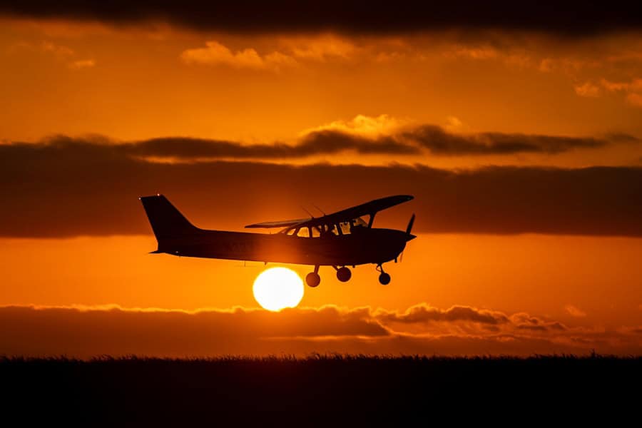 Aircraft flying at sunset with the sun low on the horizon.