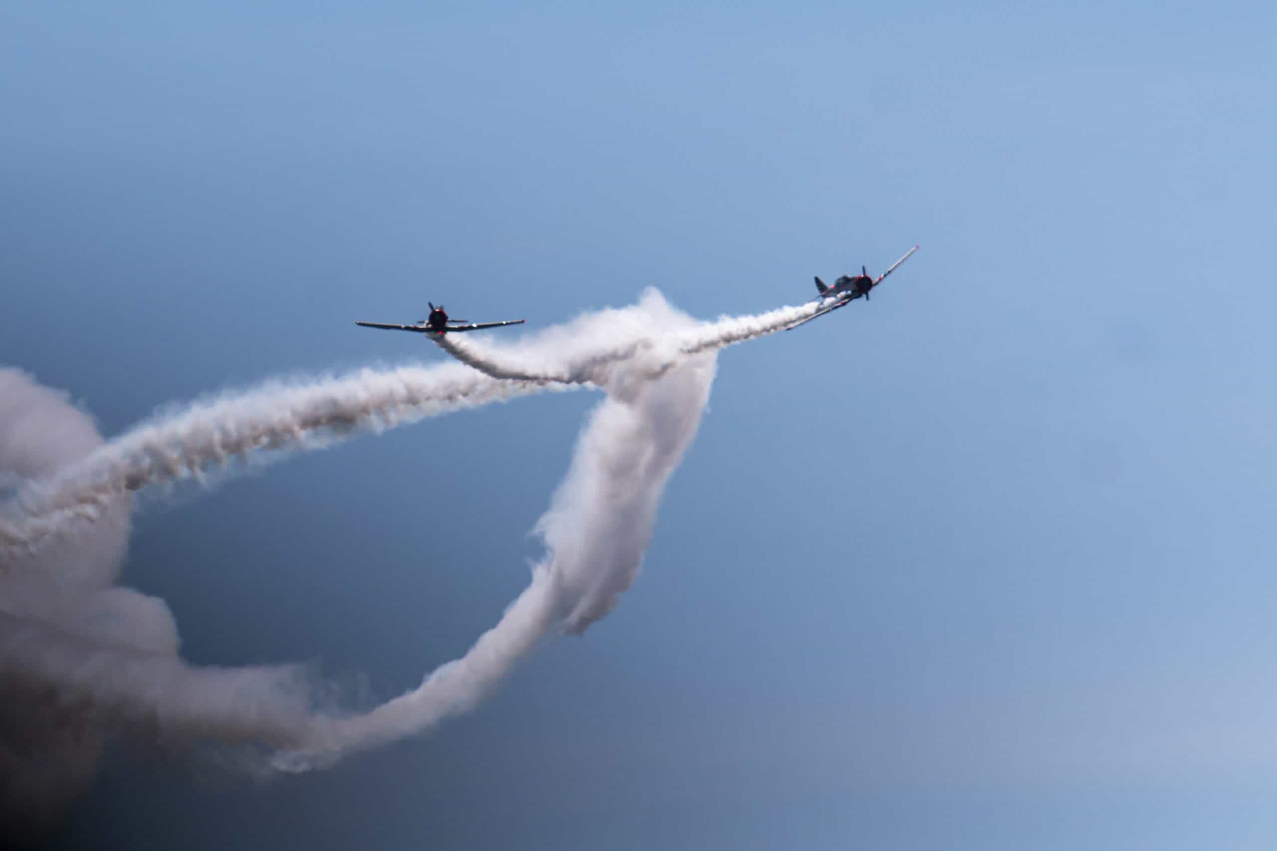 Two aircraft performing aerial maneuvers with smoke trails