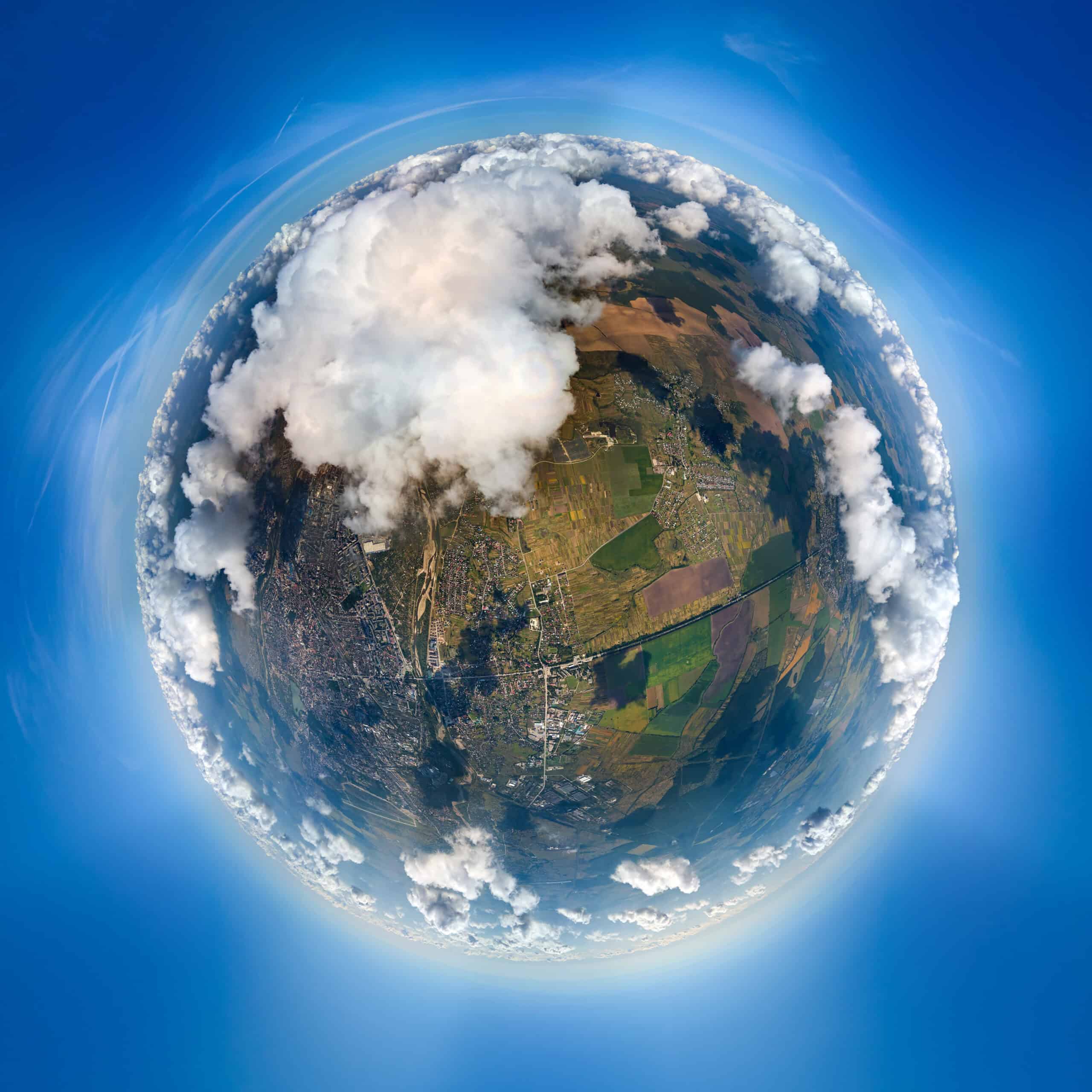 Aerial view of land and clouds captured with a fisheye lens.