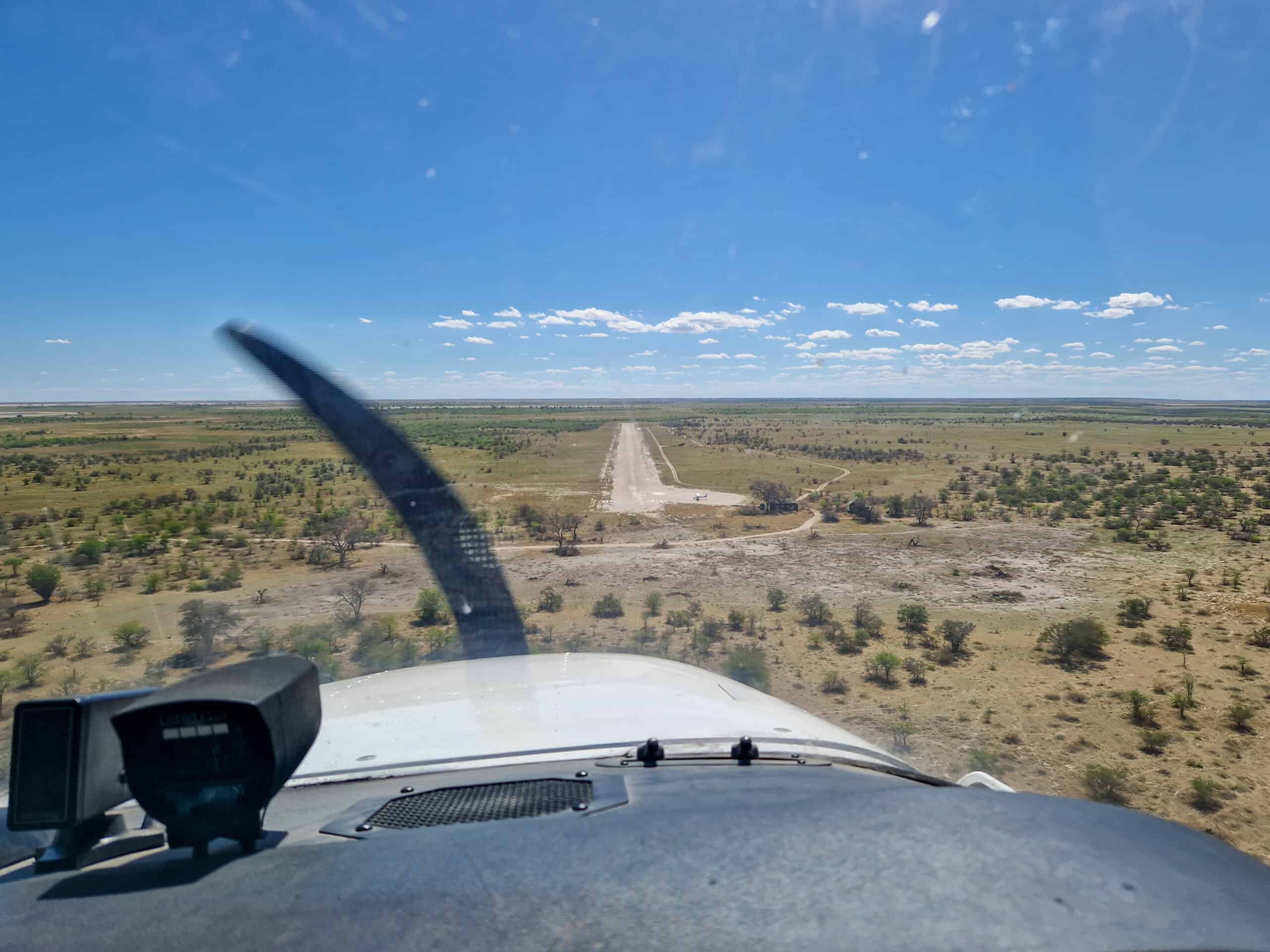Cockpit view from a GA aircraft on short final to a remote dirt airstrip — the kind of small airport where crosswind landing technique pays off