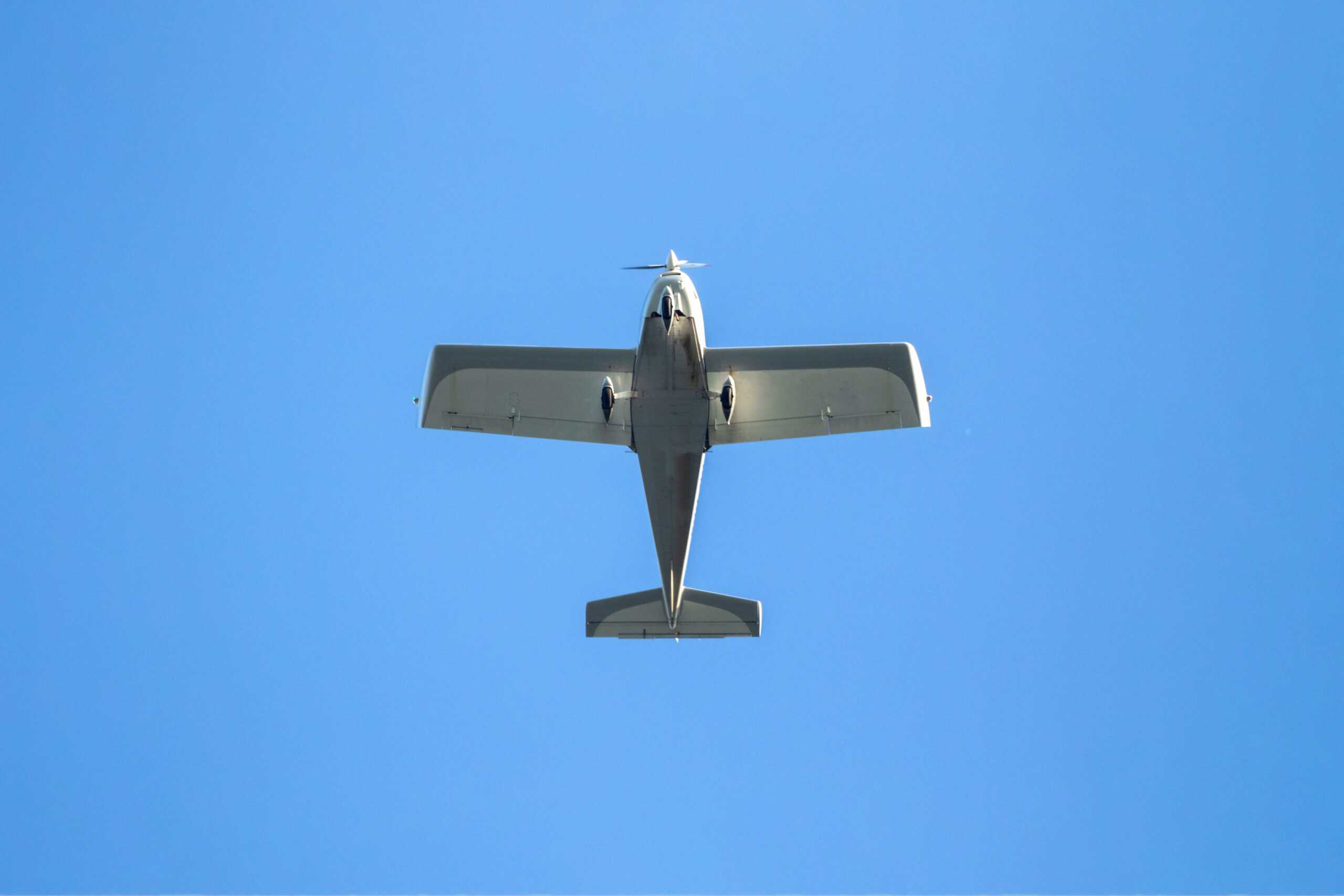 Small aircraft flying in clear blue sky during daytime.