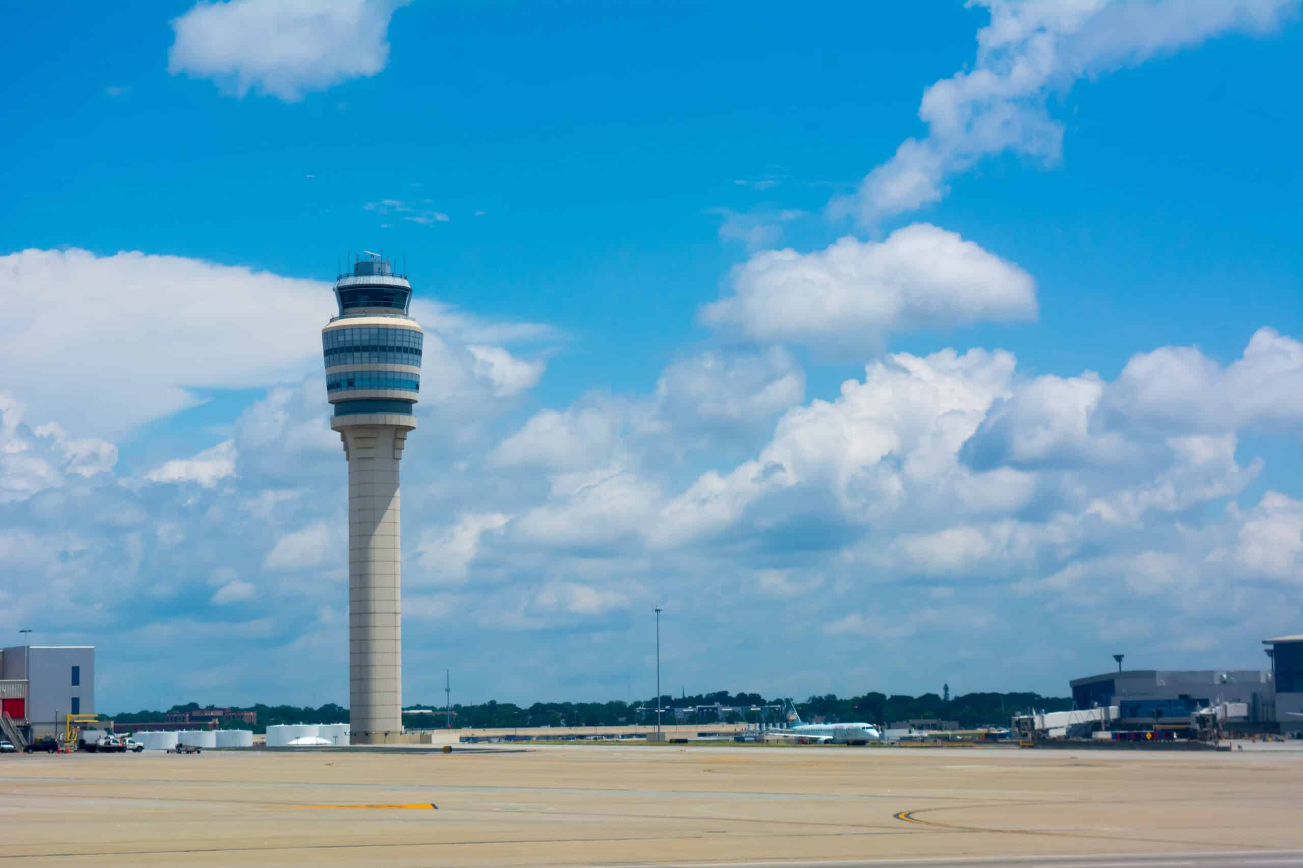 Airport control tower at an international airport under a blue sky.