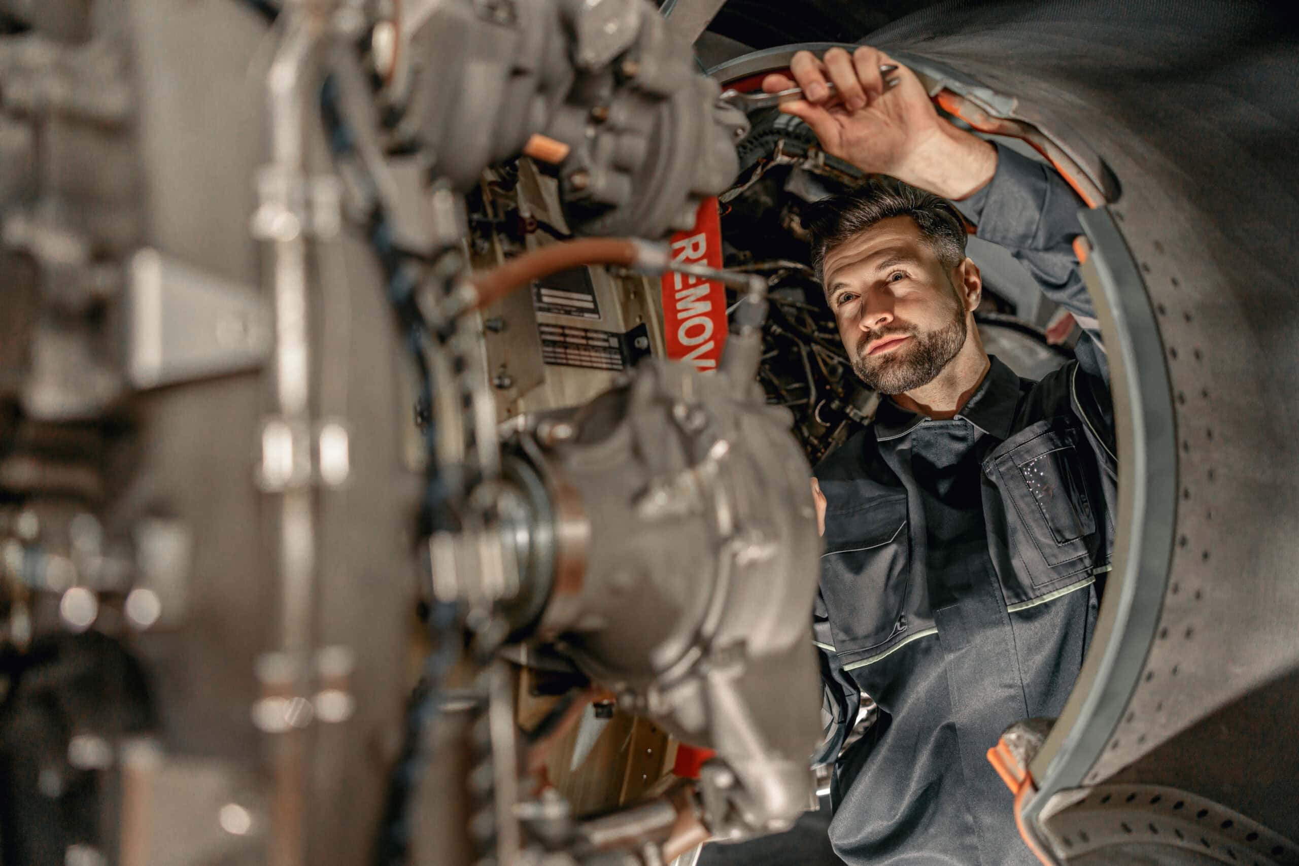 Aircraft maintenance technician inspecting engine inside aircraft fuselage.