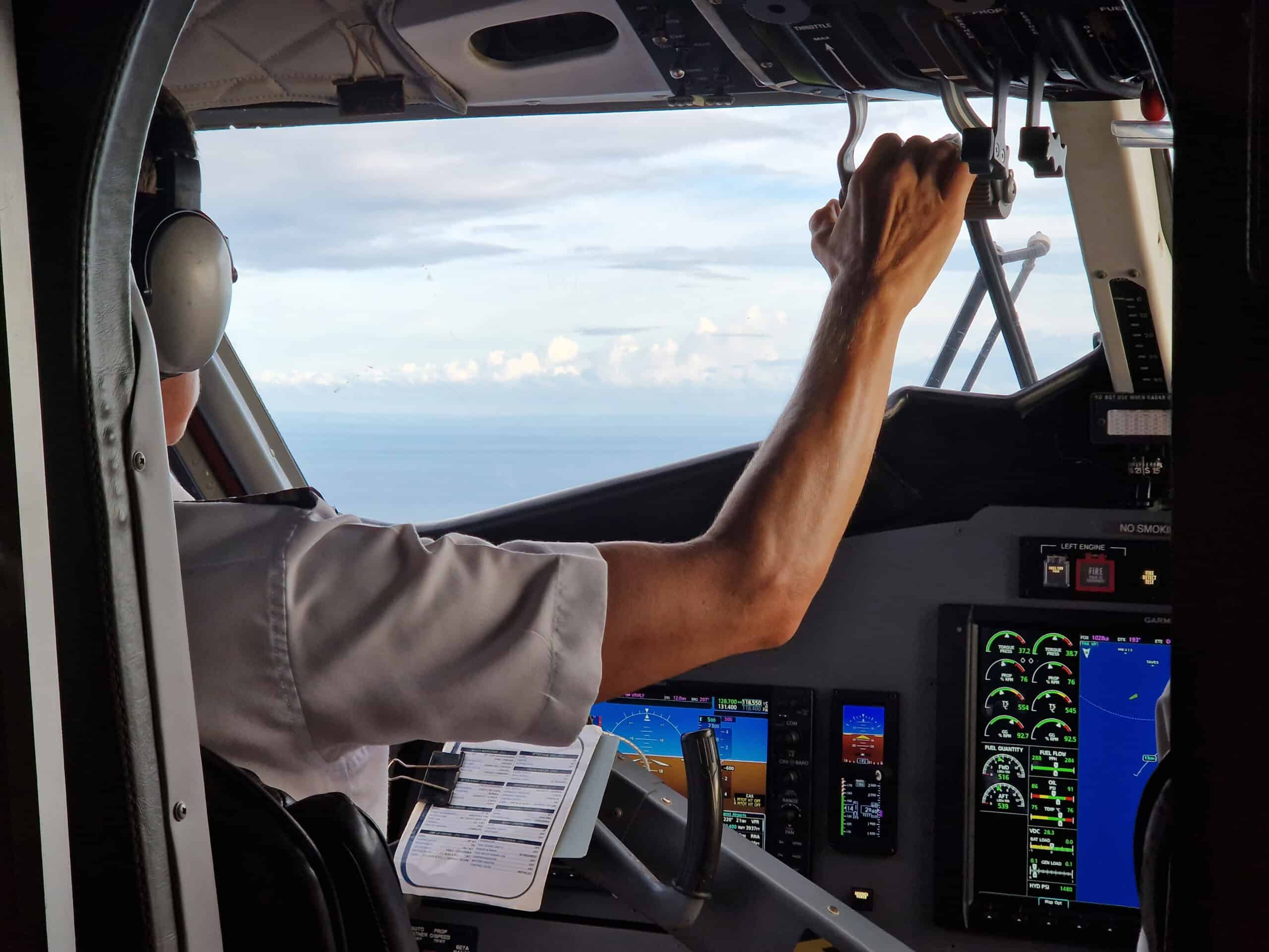 E3 Aviation Association pilot operating aircraft controls in cockpit.