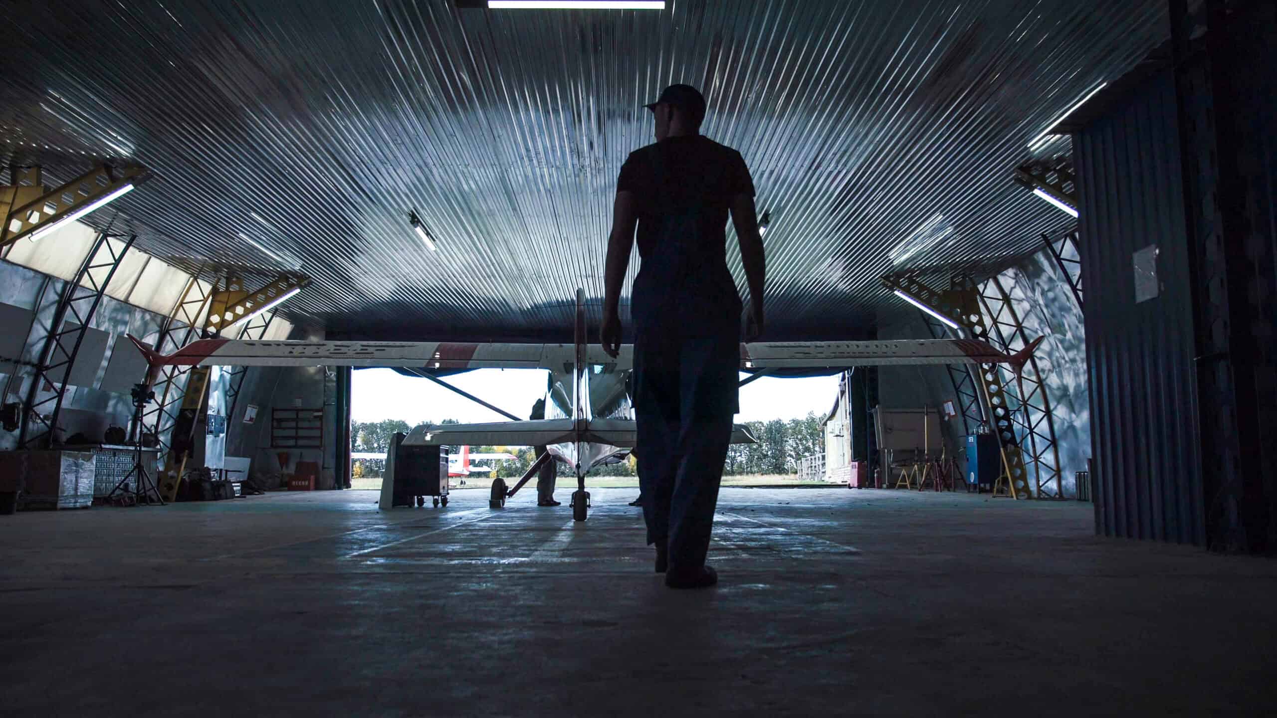 E3 Aviation Association aircraft hangar with a person walking towards a small plane.