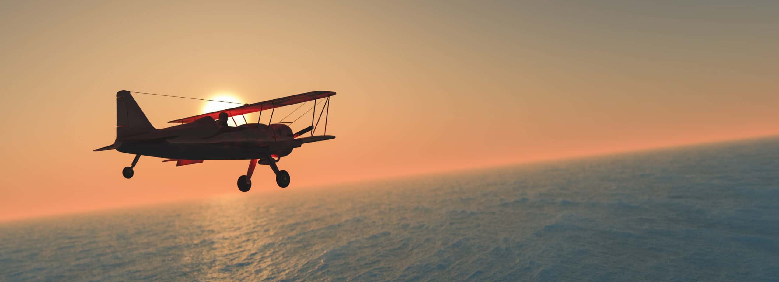 Vintage biplane silhouette flying over ocean at sunset