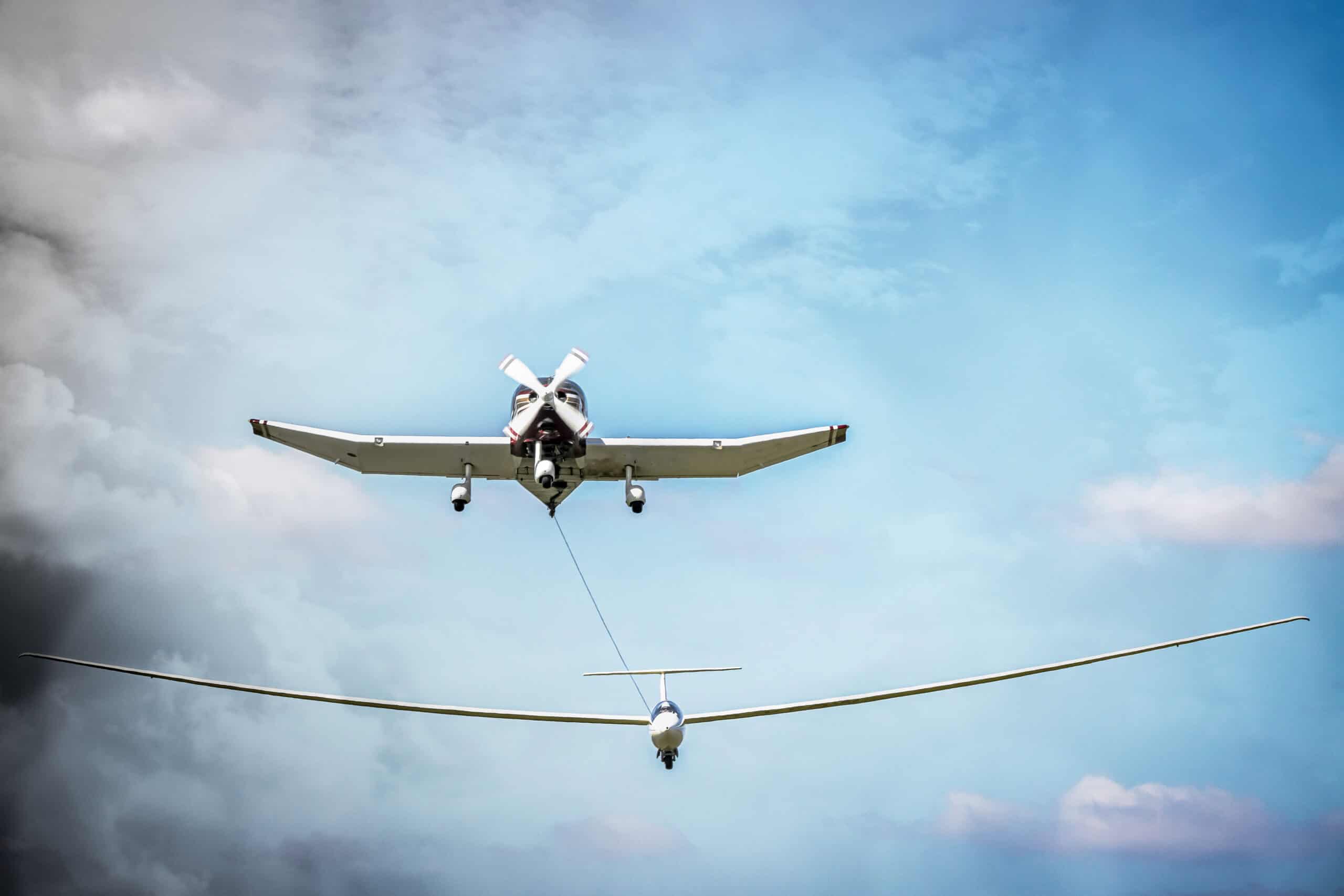 E3 Aviation Association aircraft towing drone in flight against blue sky.