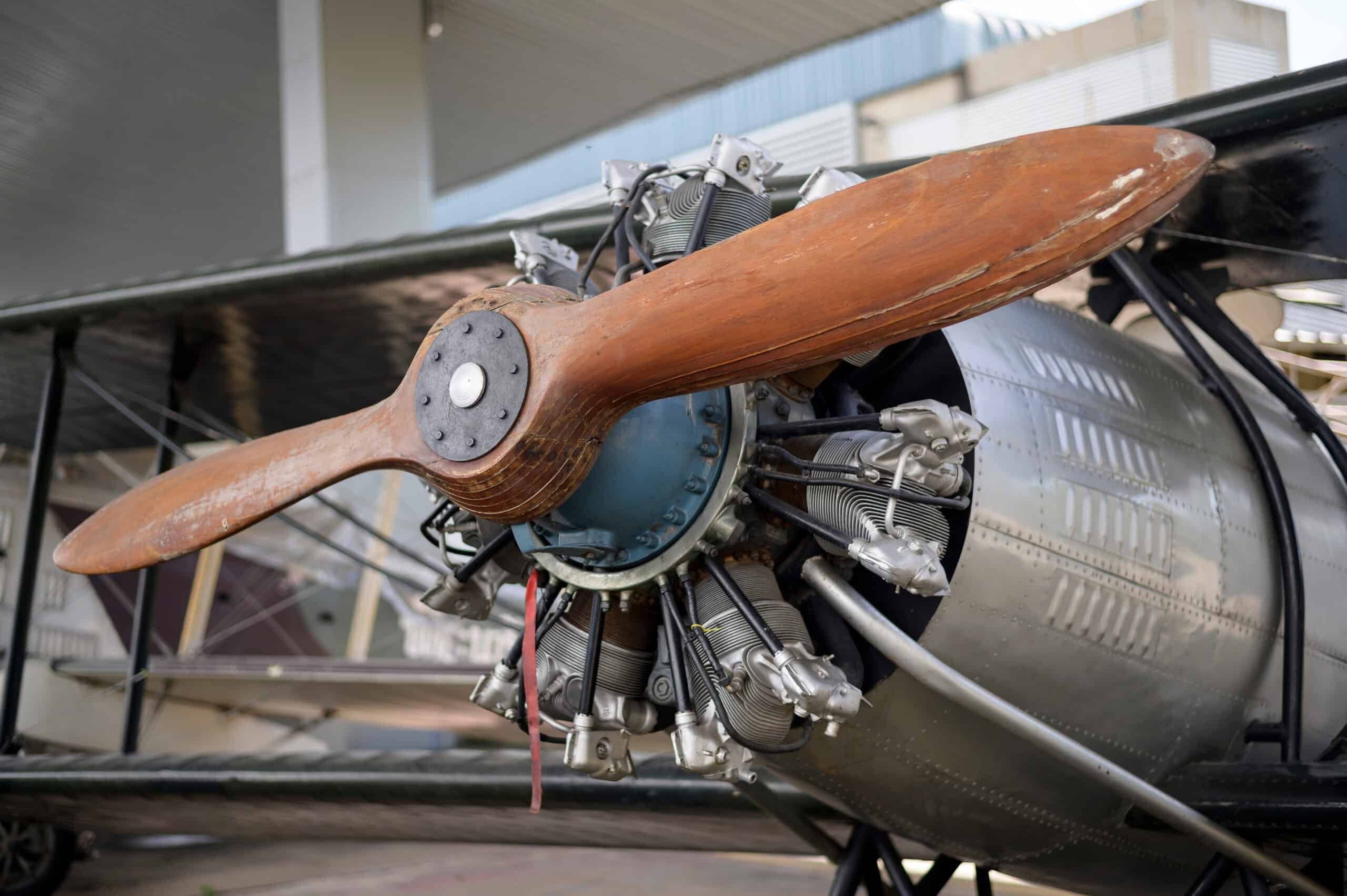 Vintage aircraft engine with wooden propeller at aviation museum.