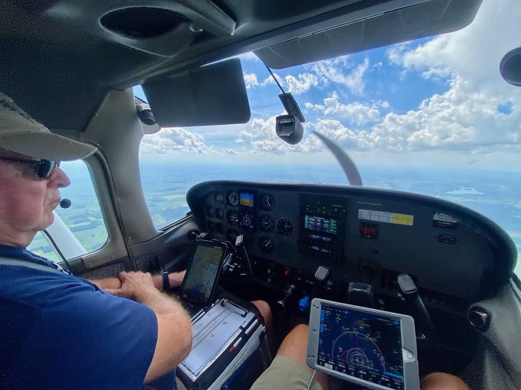 ForeFlight on iPad in cockpit alongside additional avionics — ADS-B receivers feed weather and traffic into this kind of EFB stack.