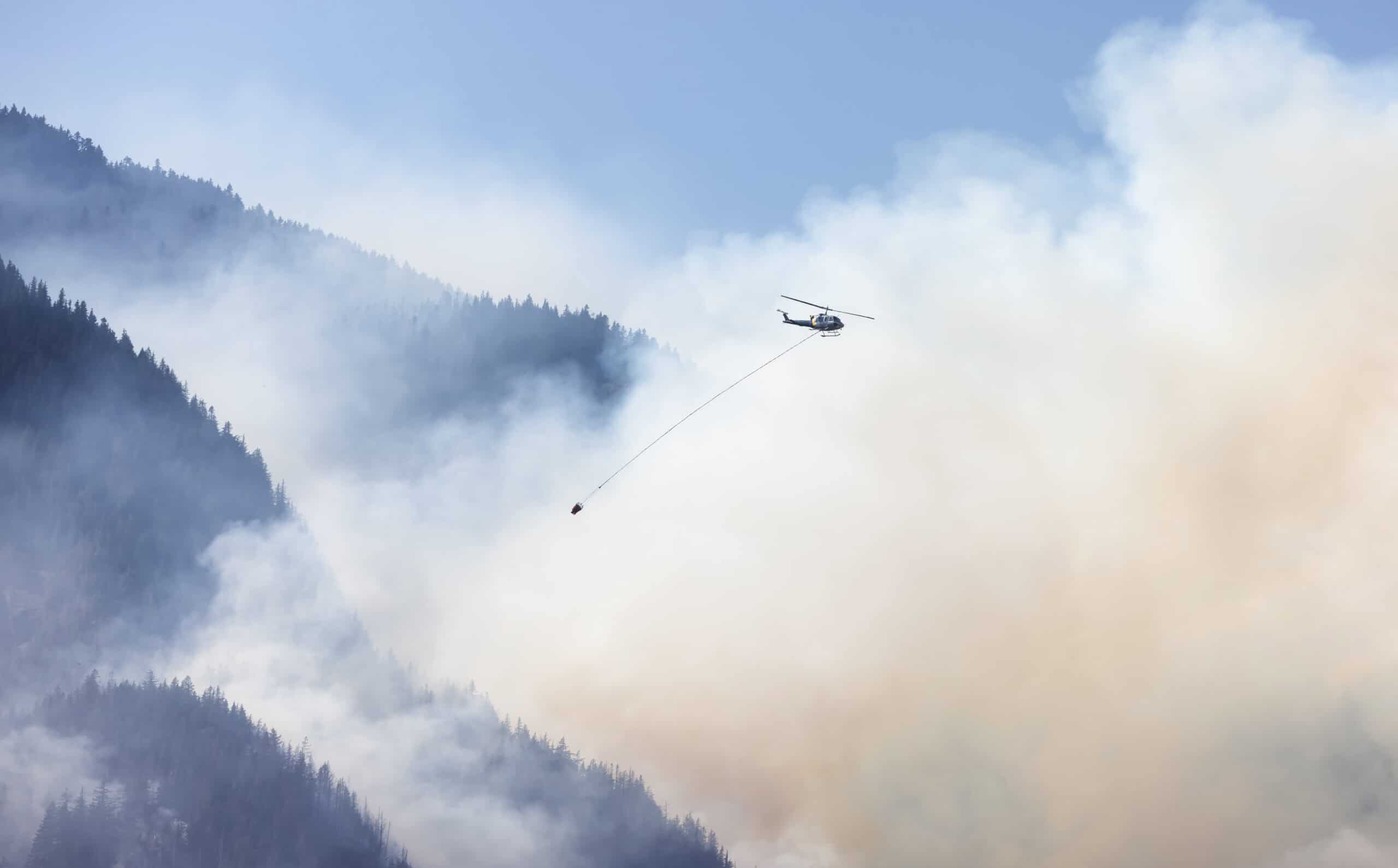 E3 Aviation Association helicopter dropping water on forest fire.