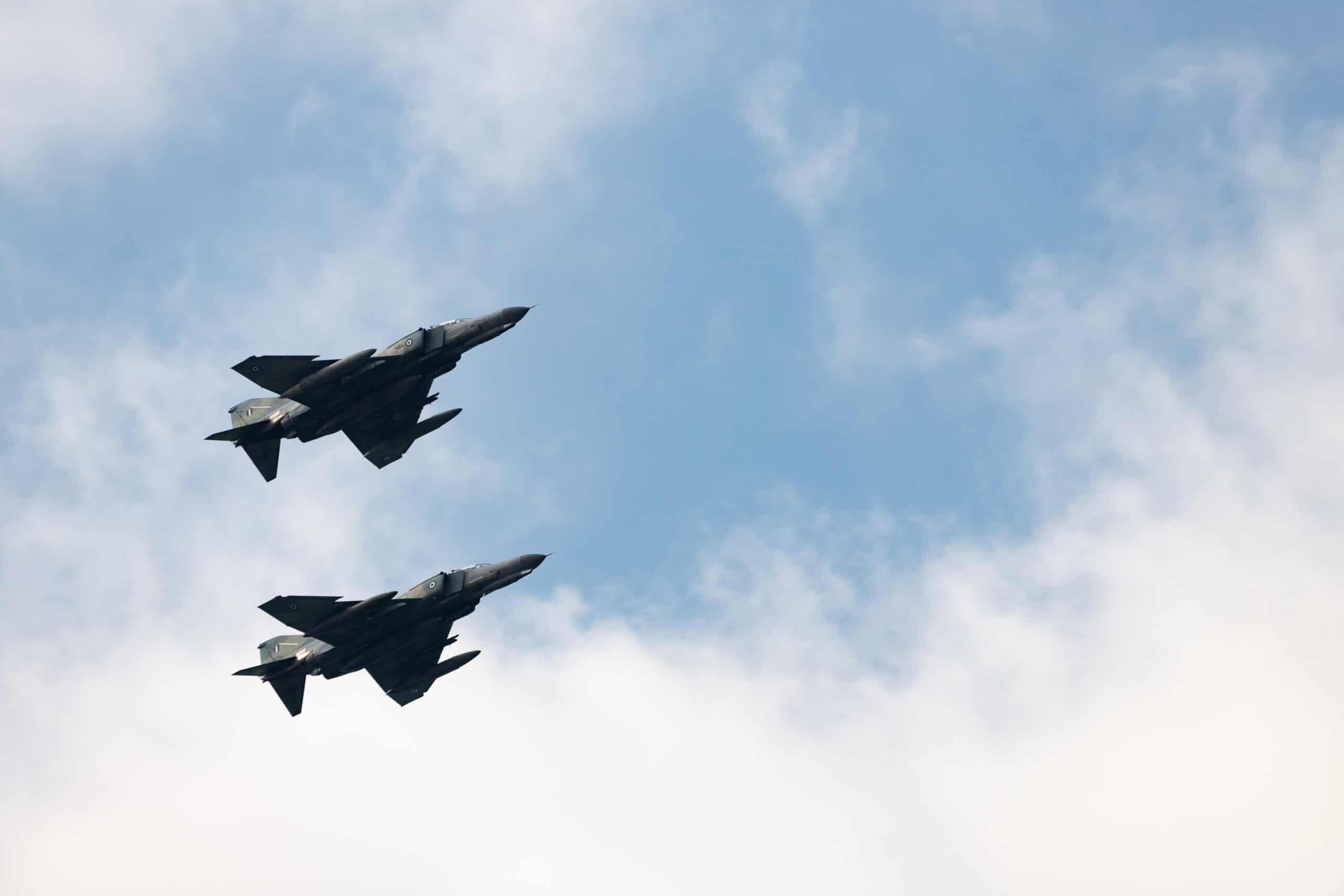 Two Soviet-era tactical fighter jets in low-level formation during combat operations