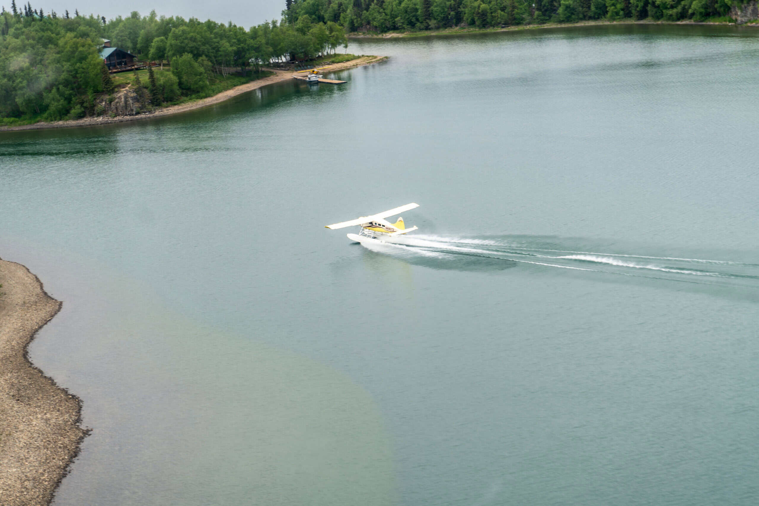overwater flying safety — yellow Beaver floatplane taking off from a lake