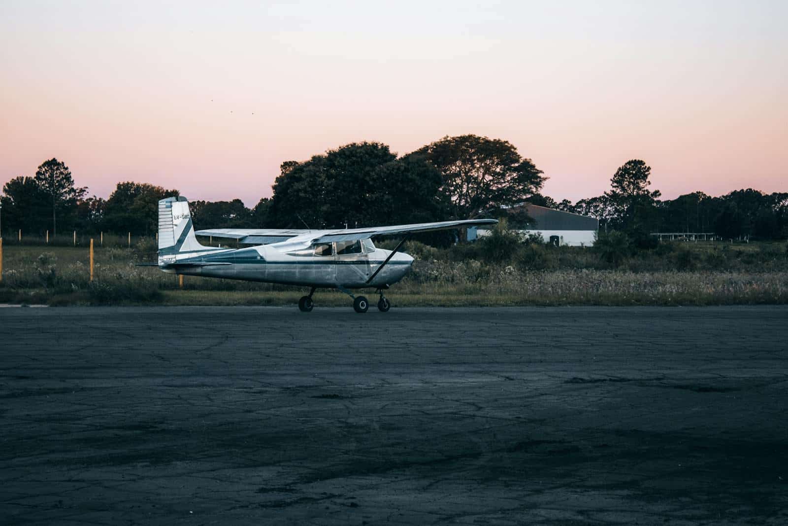 Small aircraft parked on a rural runway during sunset