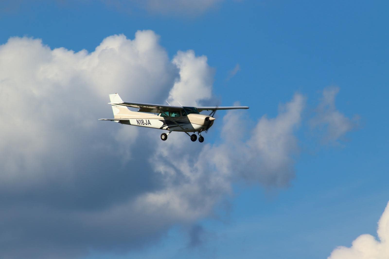 Small aircraft flying among white clouds in a clear blue sky
