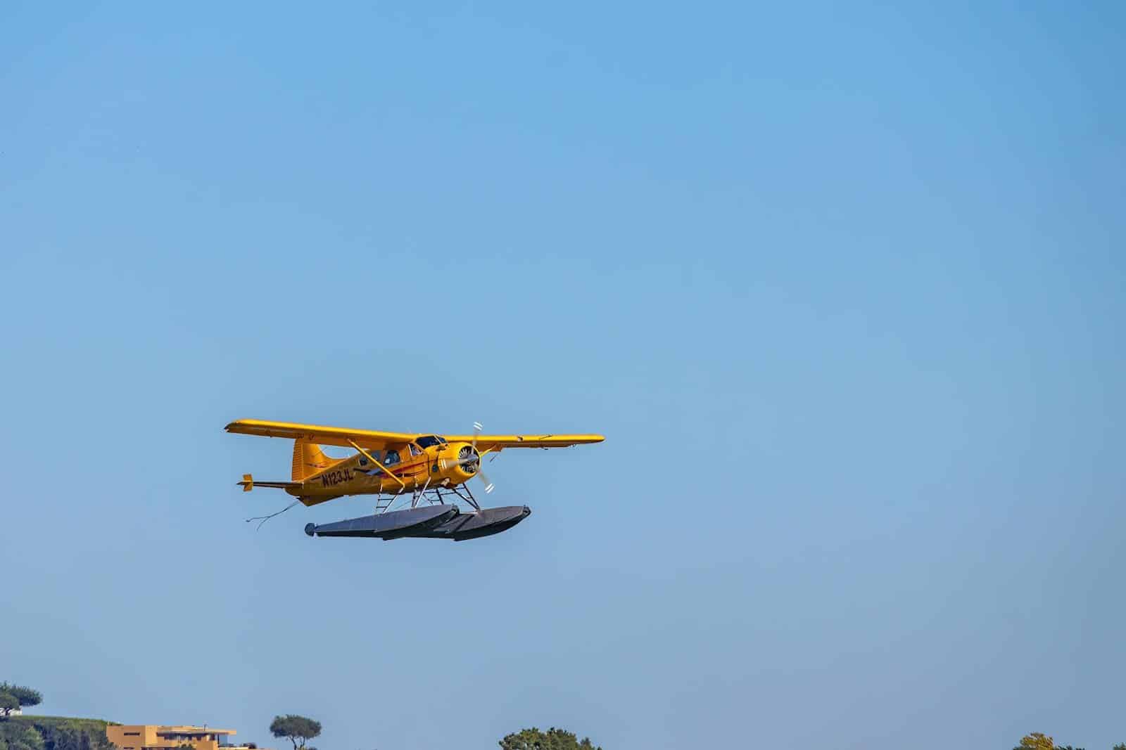 Yellow seaplane flying through a clear blue sky