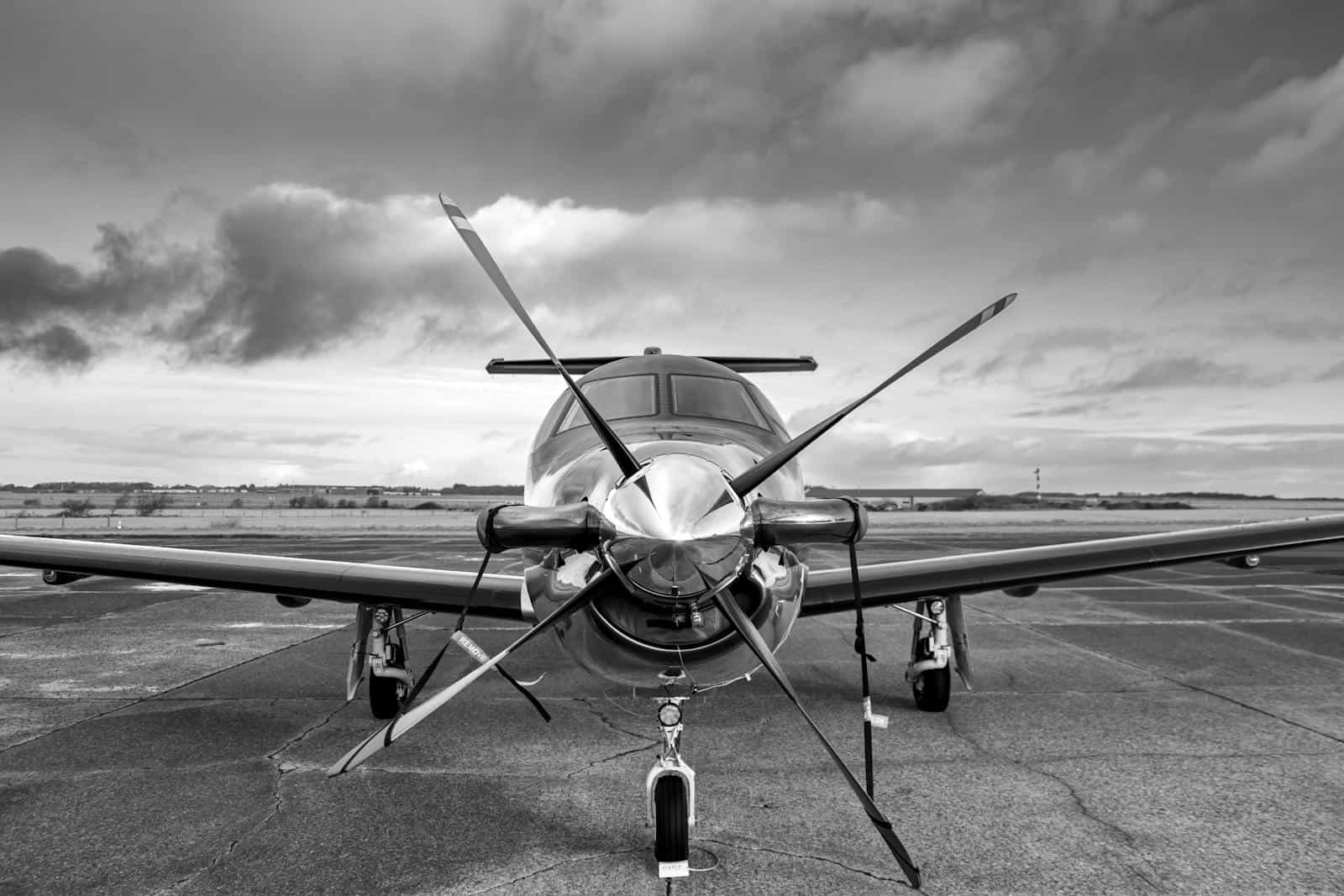 Private propeller aircraft parked on the runway with a dramatic cloudy sky in the background.