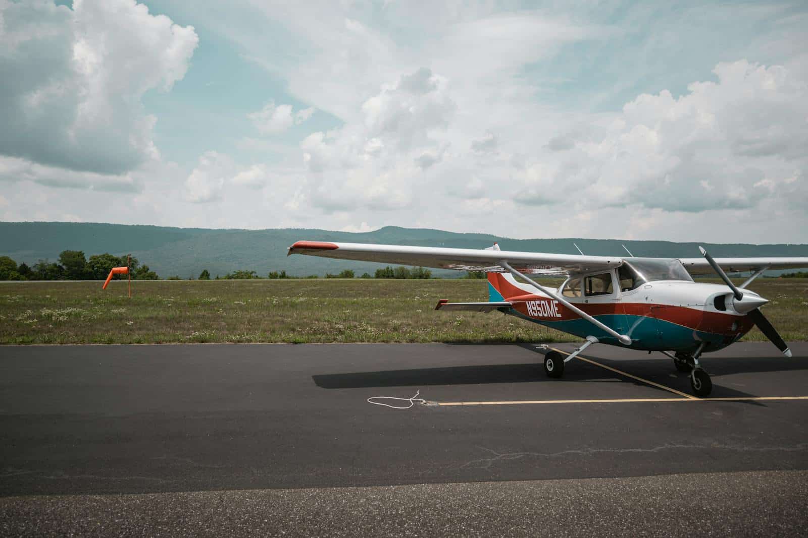 Small propeller aircraft on a rural tarmac with mountain views