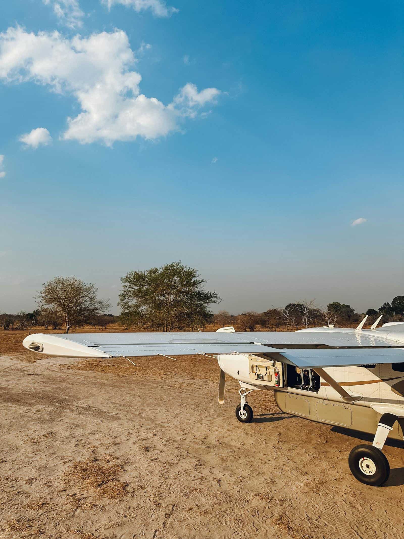 Aircraft on runway with trees and clear blue sky.