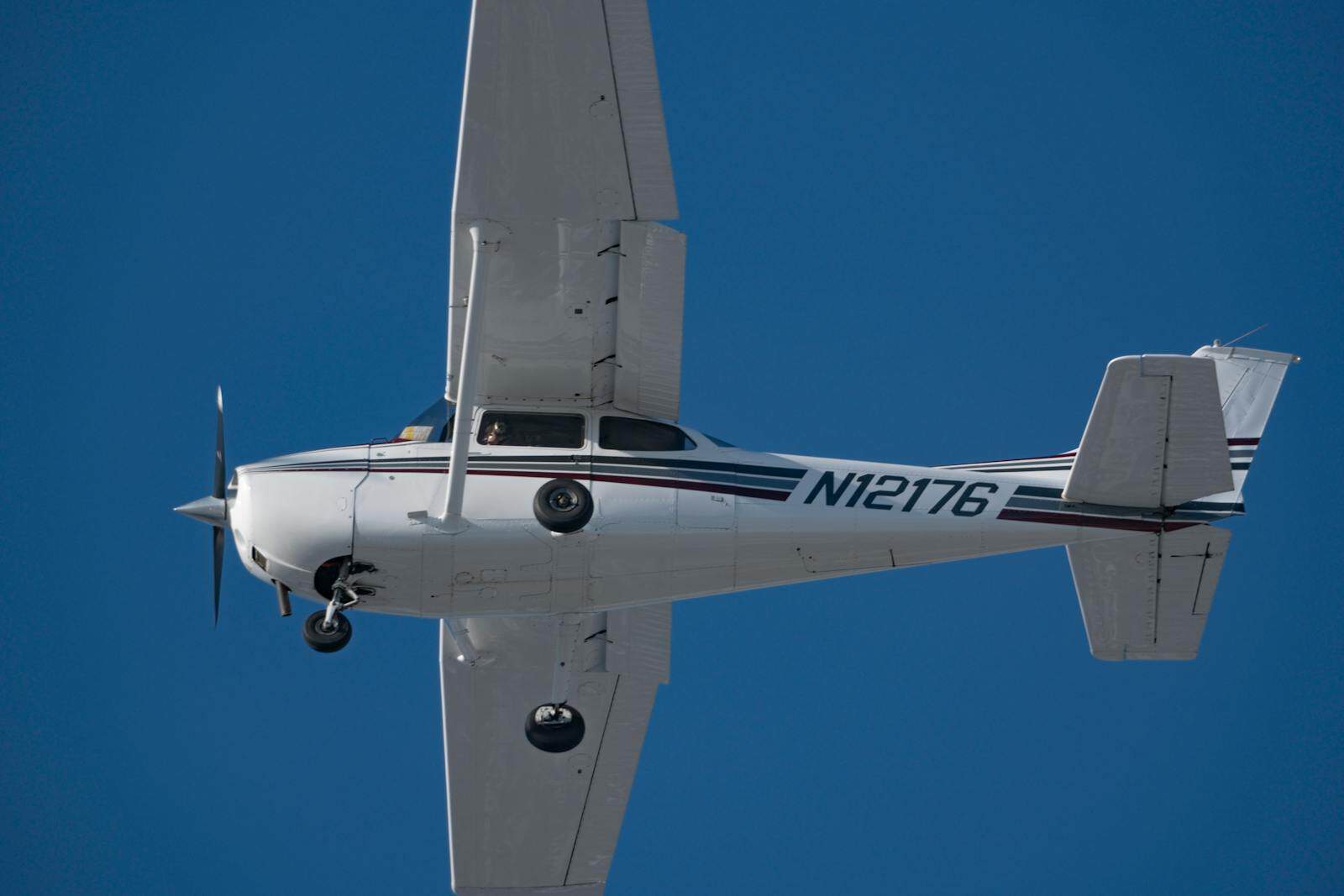Private propeller aircraft with registration N12176 flying in clear blue sky.