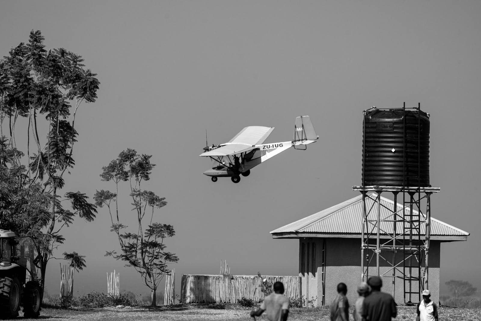 Small aircraft in flight over rural area.