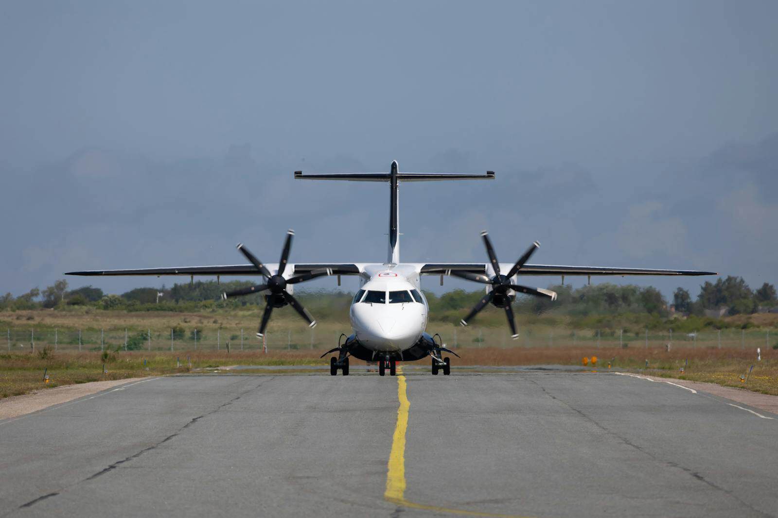 Front view of a propeller aircraft on a runway ready for takeoff