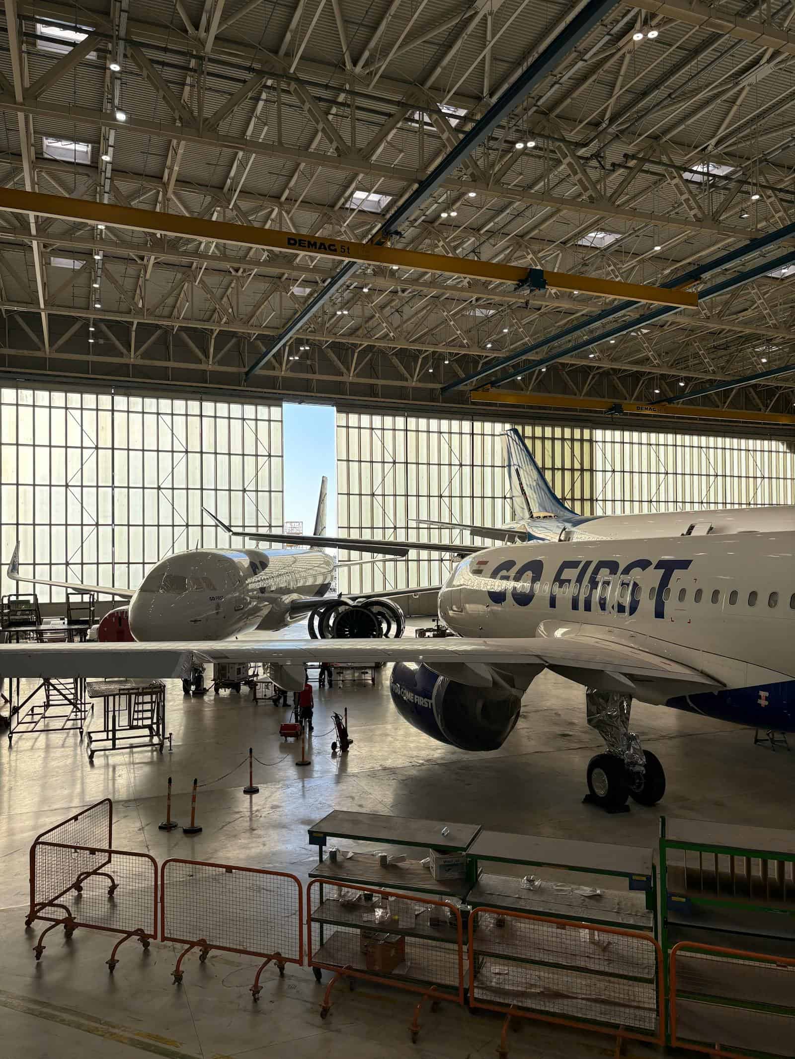 Aircraft maintenance hangar featuring two commercial airplanes inside a spacious, well-lit facility.