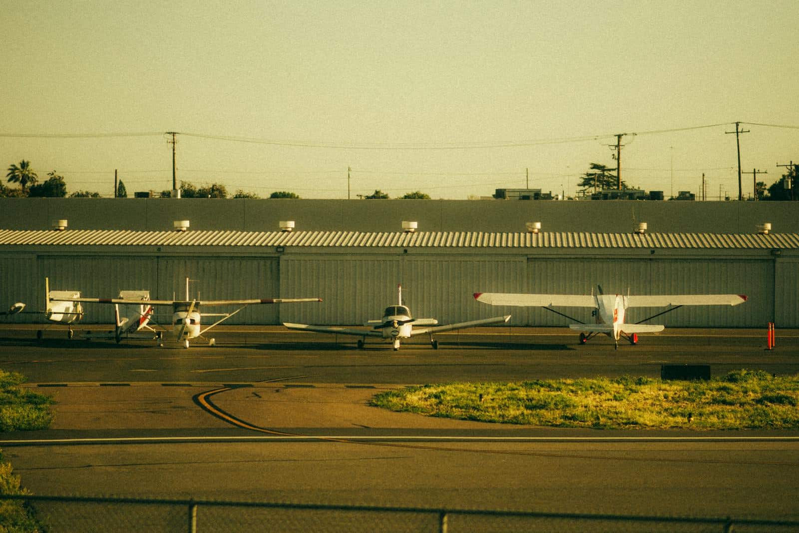Four private general aviation airplanes parked on a sunlit runway