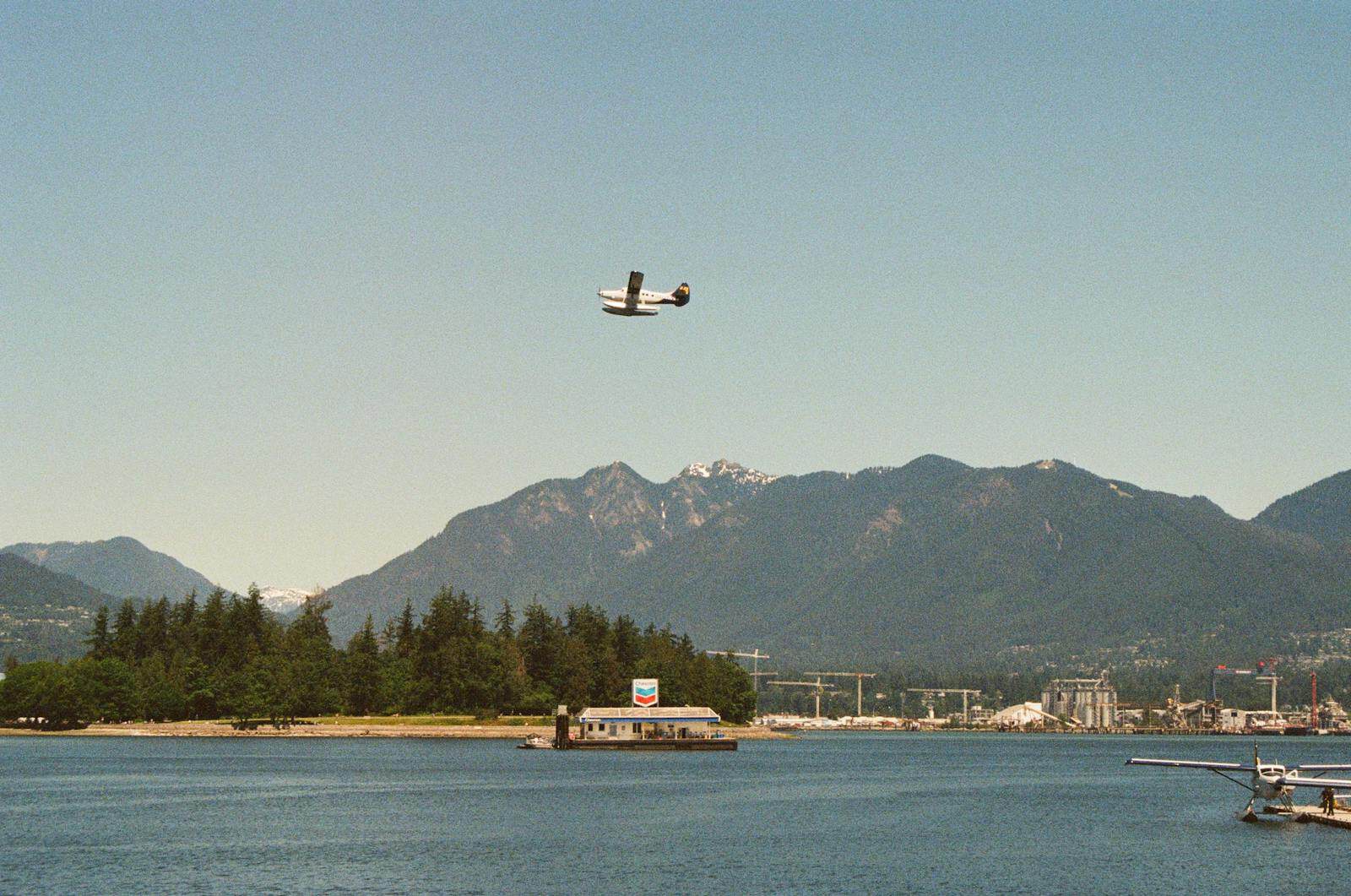 Seaplane flying over a harbor with mountain backdrop