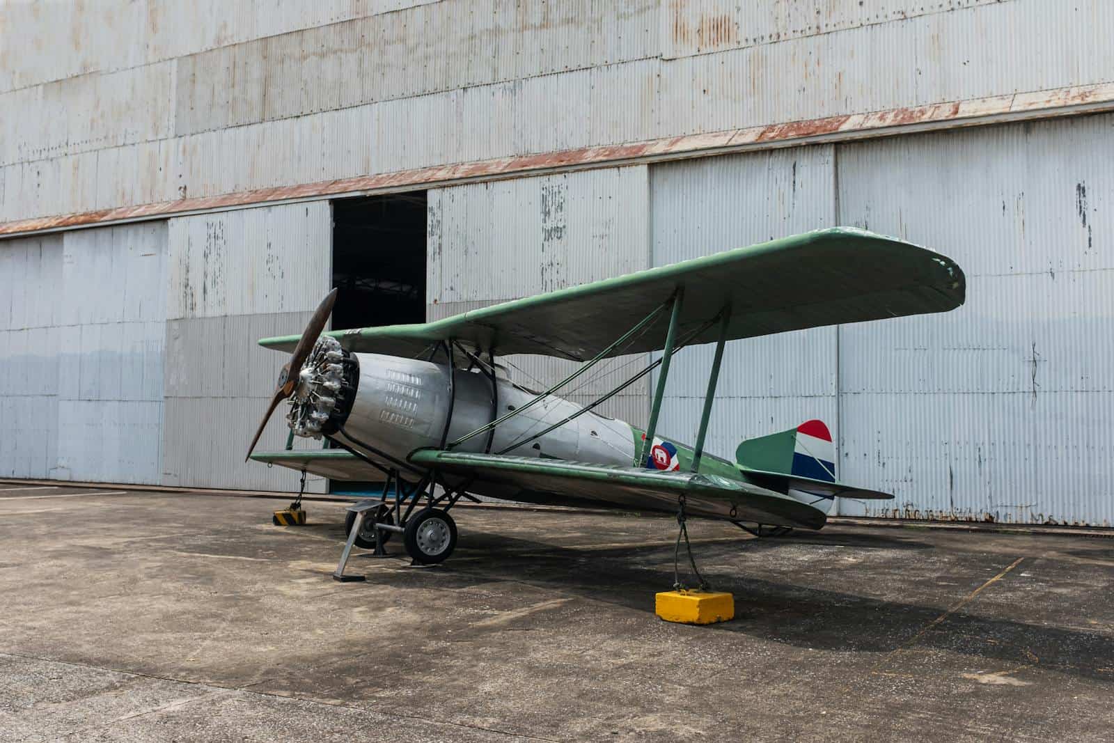 Classic vintage biplane parked outside an aircraft hangar
