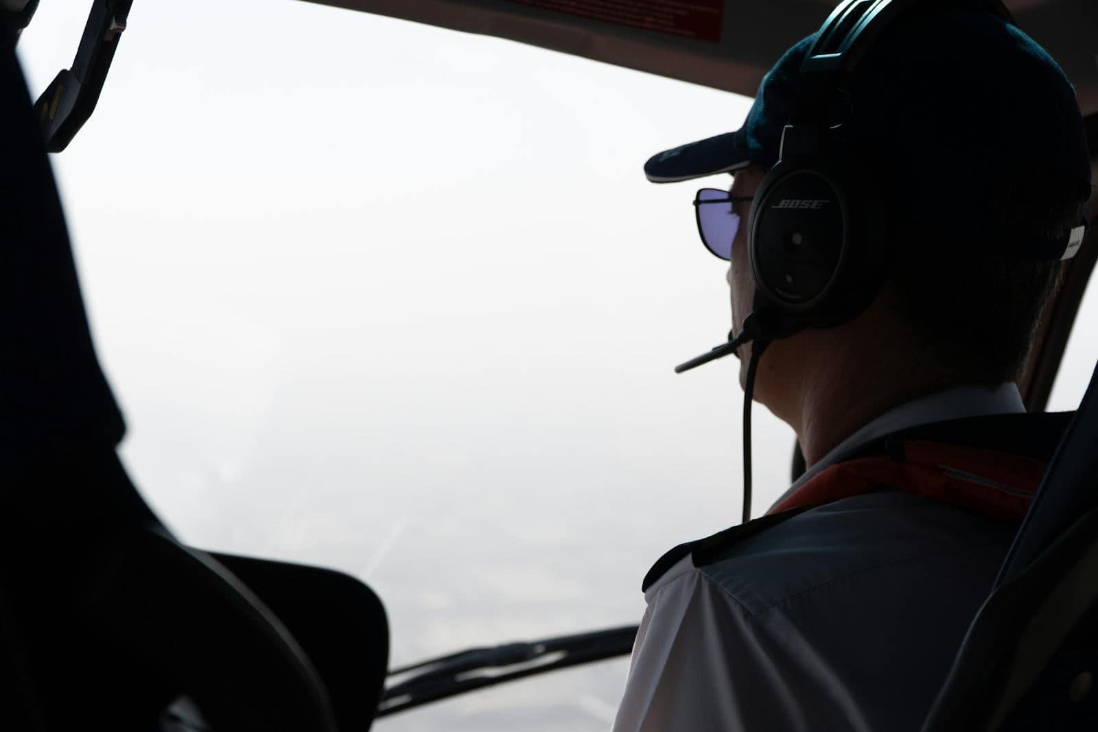 Pilot wearing headset looking out a general aviation cockpit window during flight