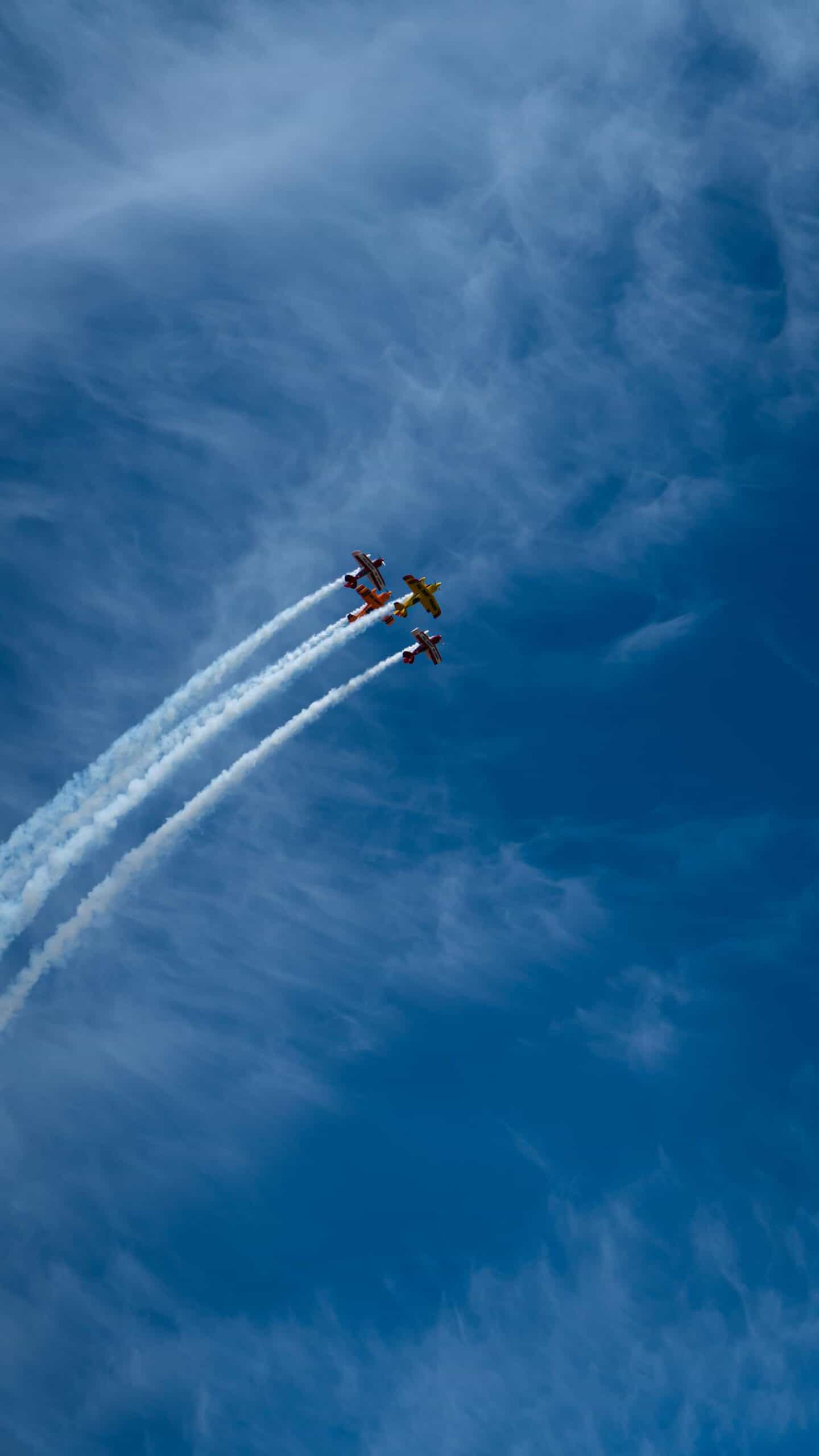 Three aerobatic aircraft flying in close formation against a clear sky