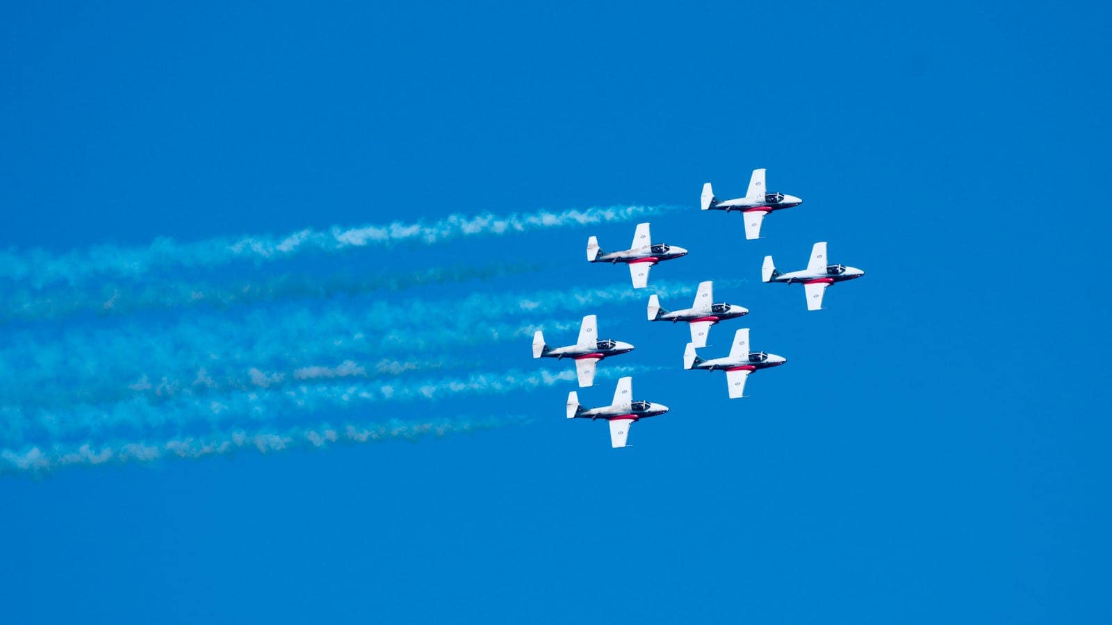 Six aircraft in formation performing aerobatic maneuvers