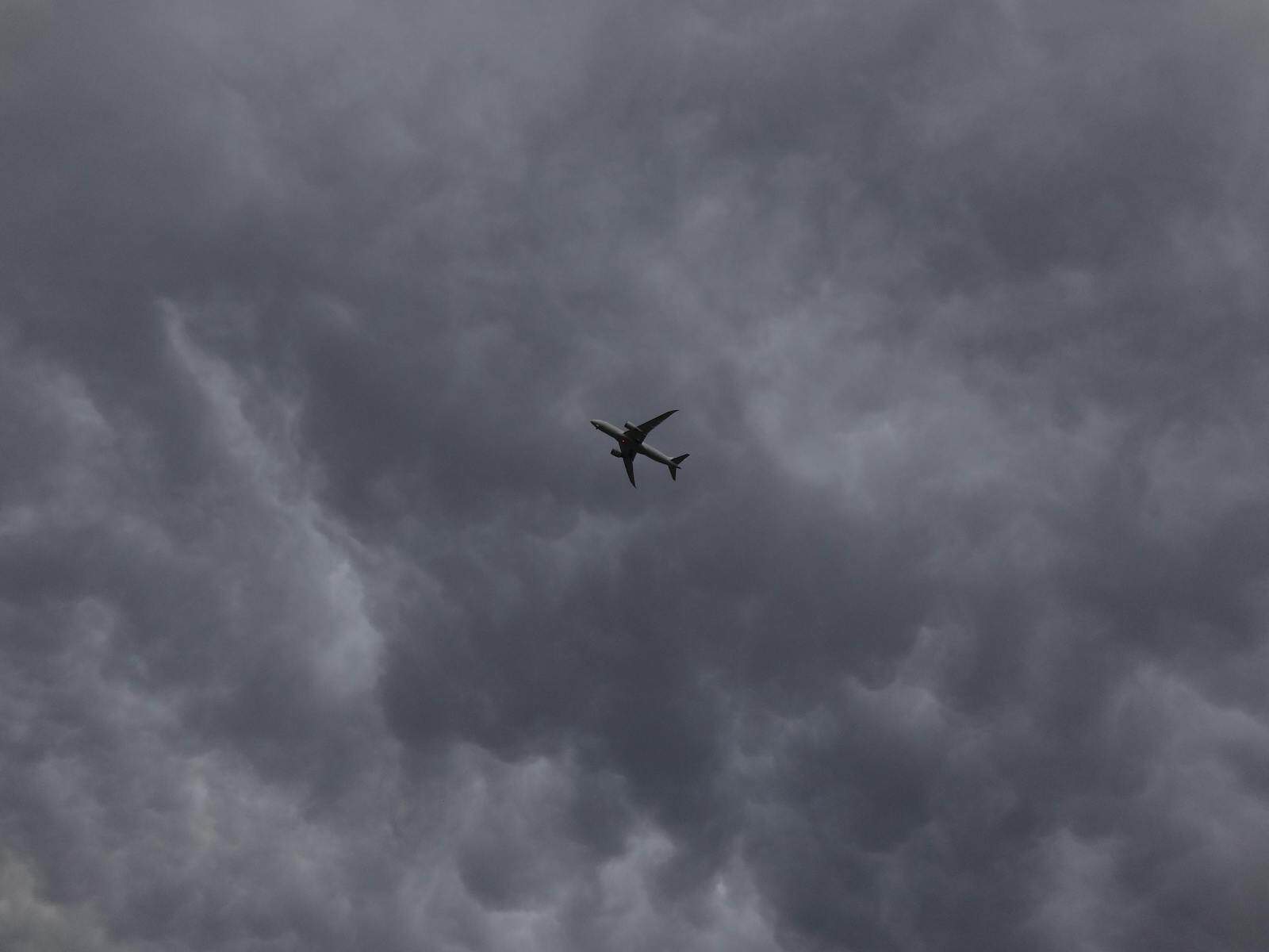 Silhouette of a small aircraft against dark storm clouds