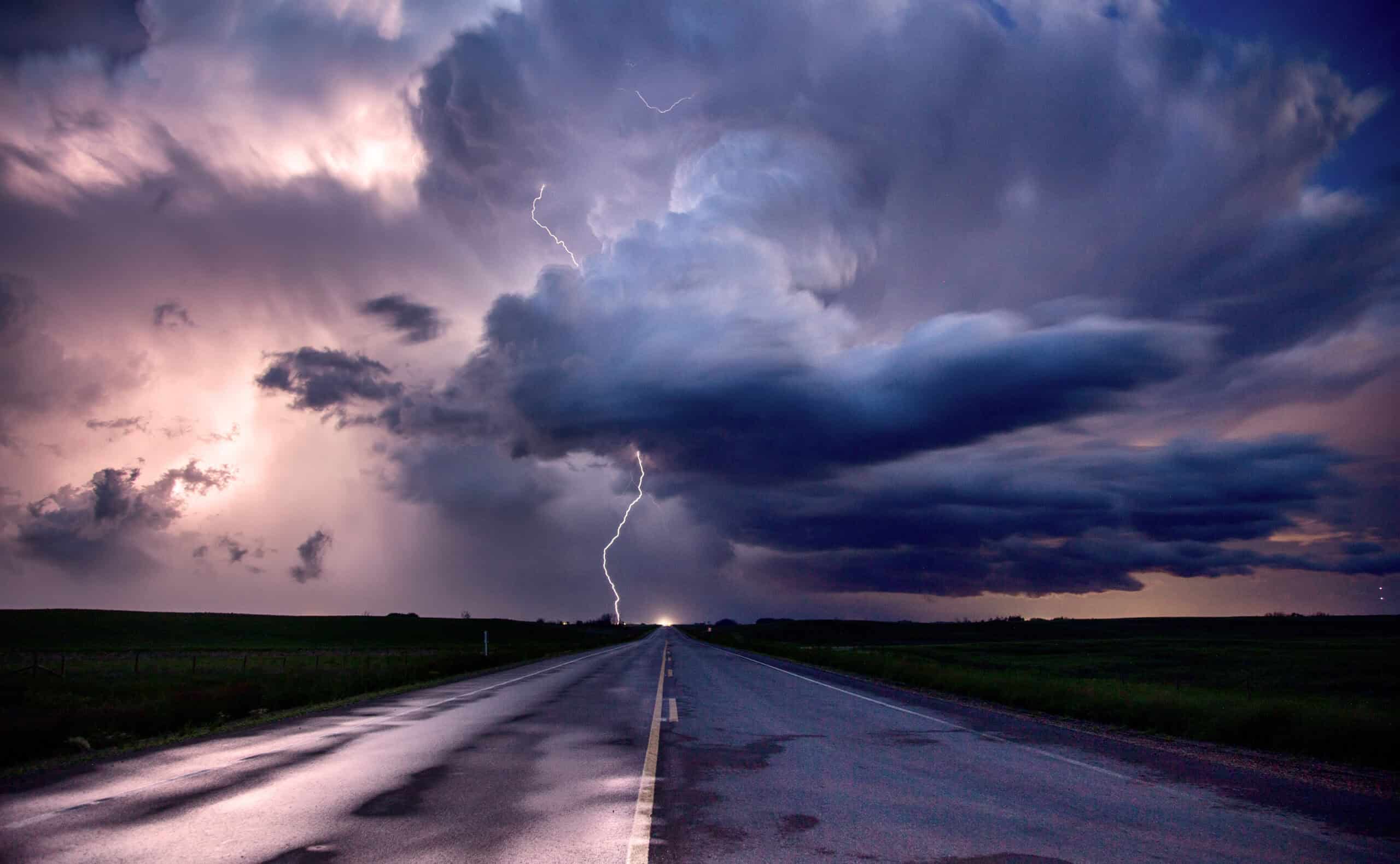 Isolated supercell thunderstorm with lightning over a prairie road — the kind of single cell airborne weather radar would paint at 30 to 40 nautical miles for early thunderstorm avoidance