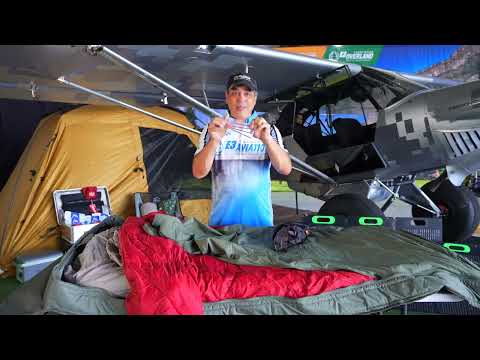 The Born Outdoor airplane camping bedroll fully unrolled with the red down quilt visible inside the green ripstop shell.
