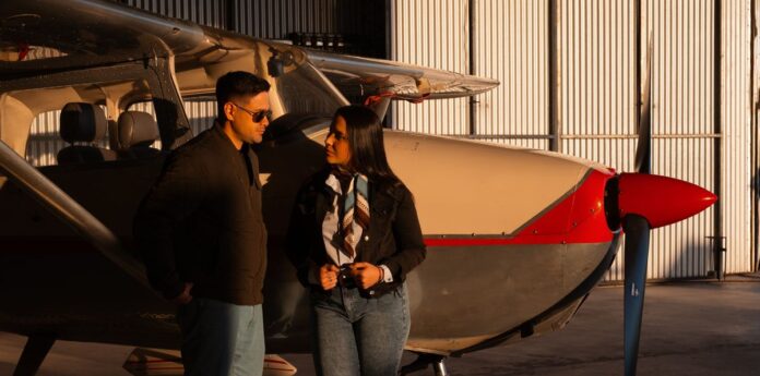 Aviation Enthusiasts Discussing Aircraft Two aviation enthusiasts talking near a small aircraft inside a hangar.