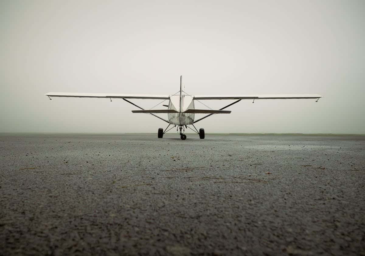 Small private aircraft on runway in foggy conditions.