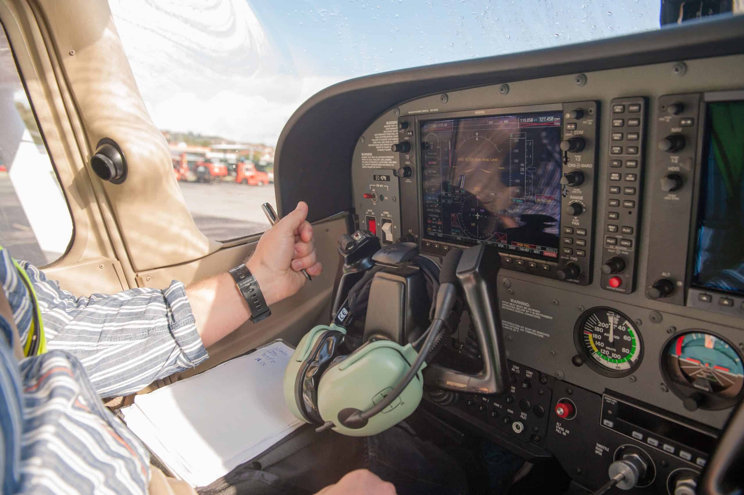 A GA pilot at a glass PFD with analog backup gauges — the modern panel architecture that removes vacuum system failure from the failure tree.