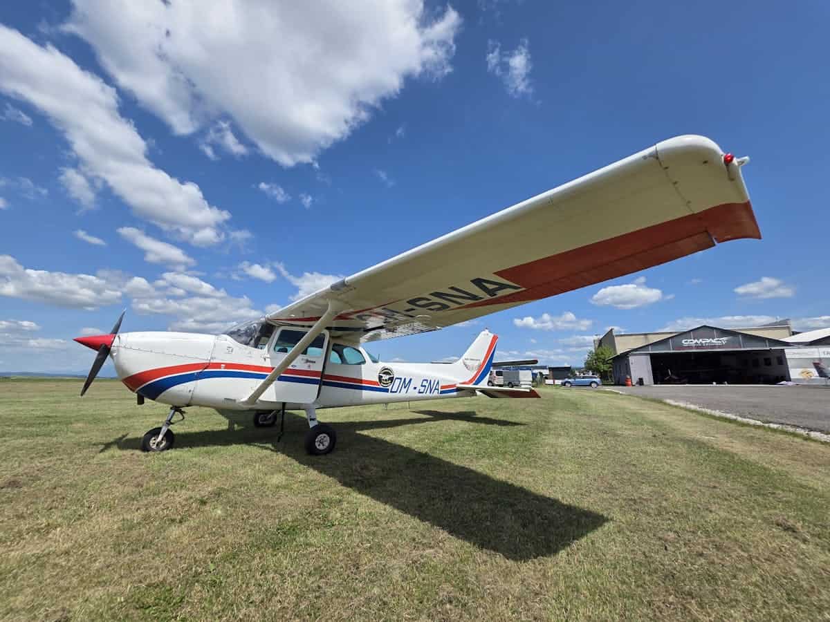 Small propeller aircraft parked on grass at an airfield under a blue sky.
