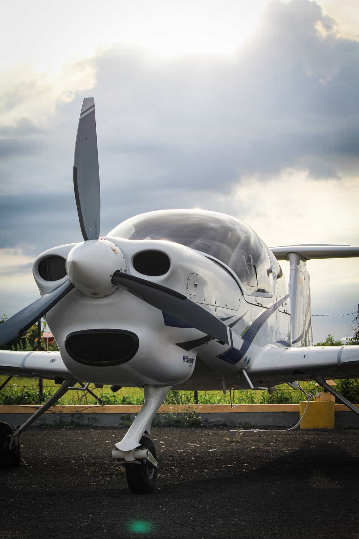 Small propeller aircraft parked outdoors under cloudy sky.