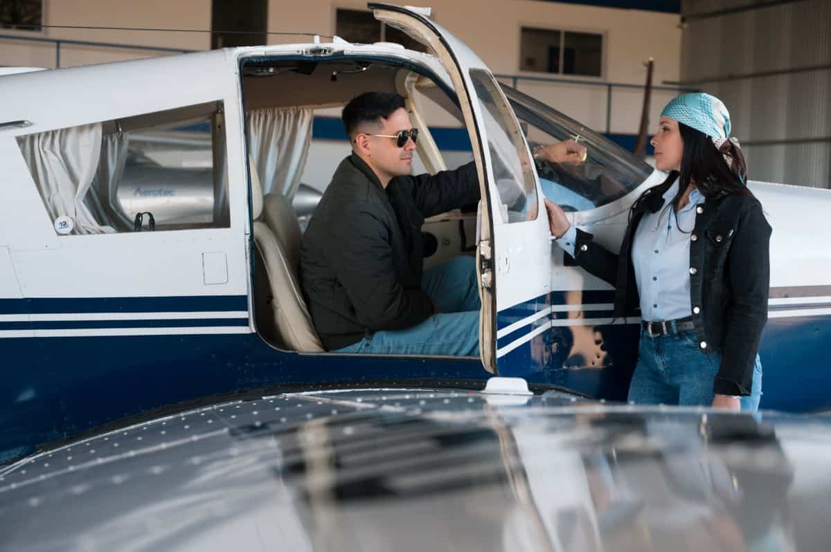 Pilot and passenger preparing for flight in small aircraft at airport.