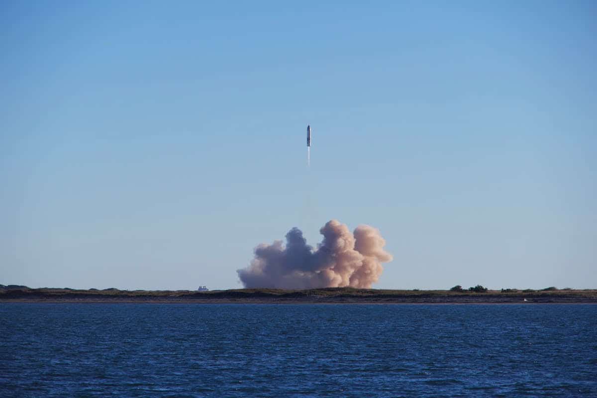 Rocket launch with smoke trails viewed across the ocean