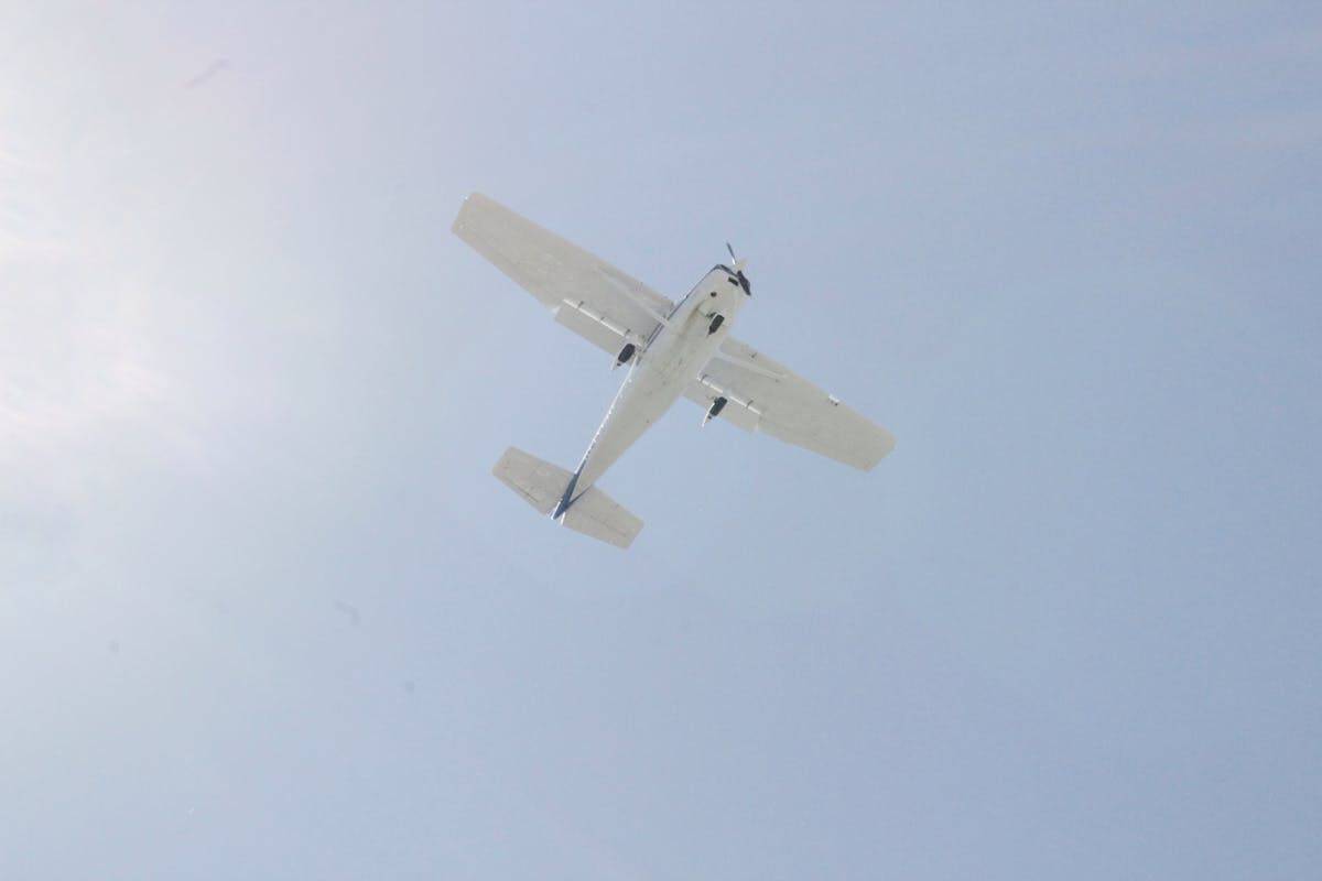 White Cessna aircraft flying against blue sky
