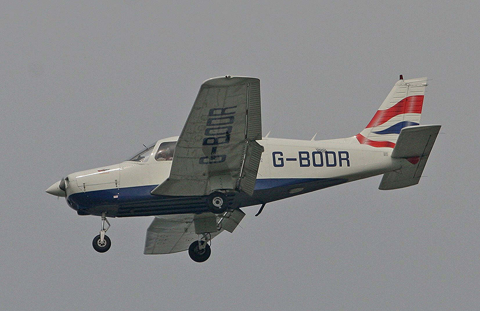 Small private aircraft flying in cloudy sky for aviation article.